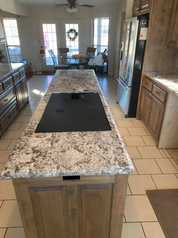 Speckled granite kitchen island and perimeter countertops in a traditional oak kitchen