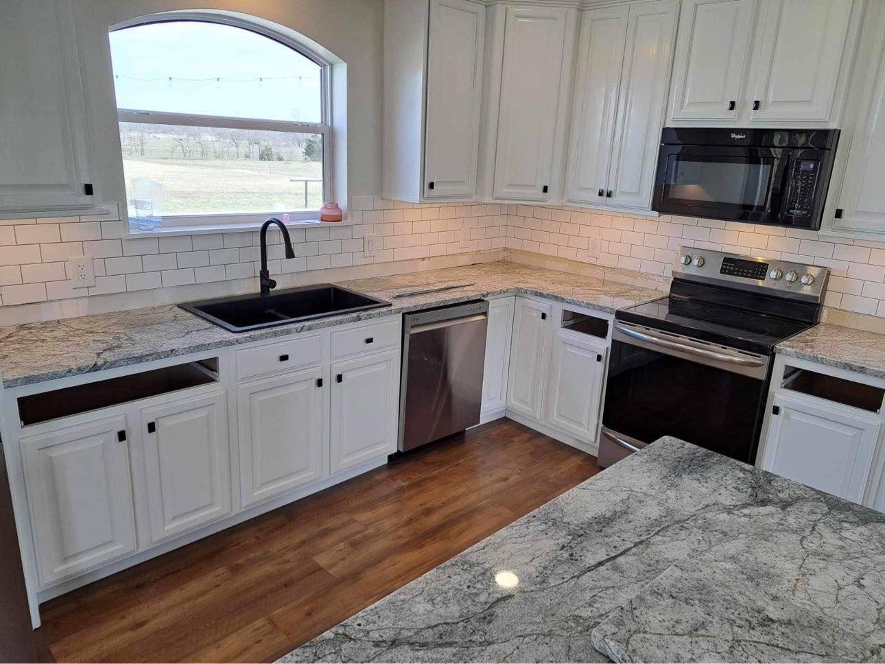 L-shaped granite countertops with undermount sink in a white kitchen