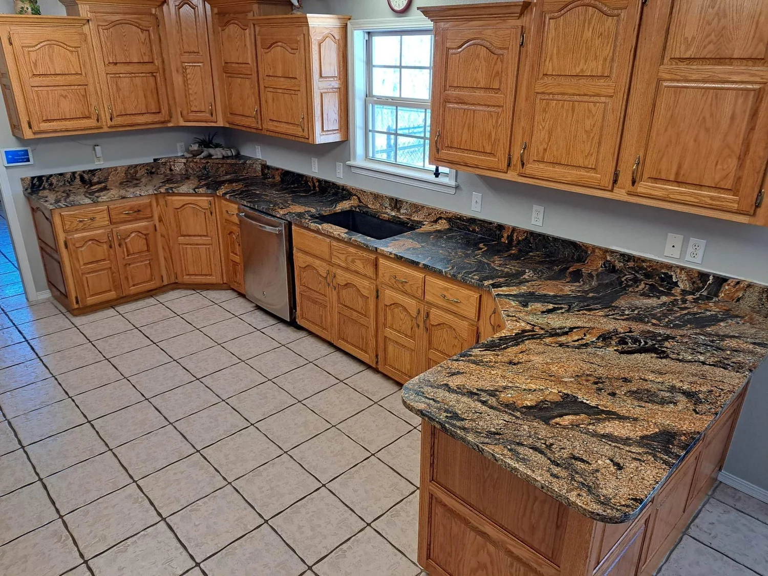 Granite countertops wrapping an oak kitchen with a corner window