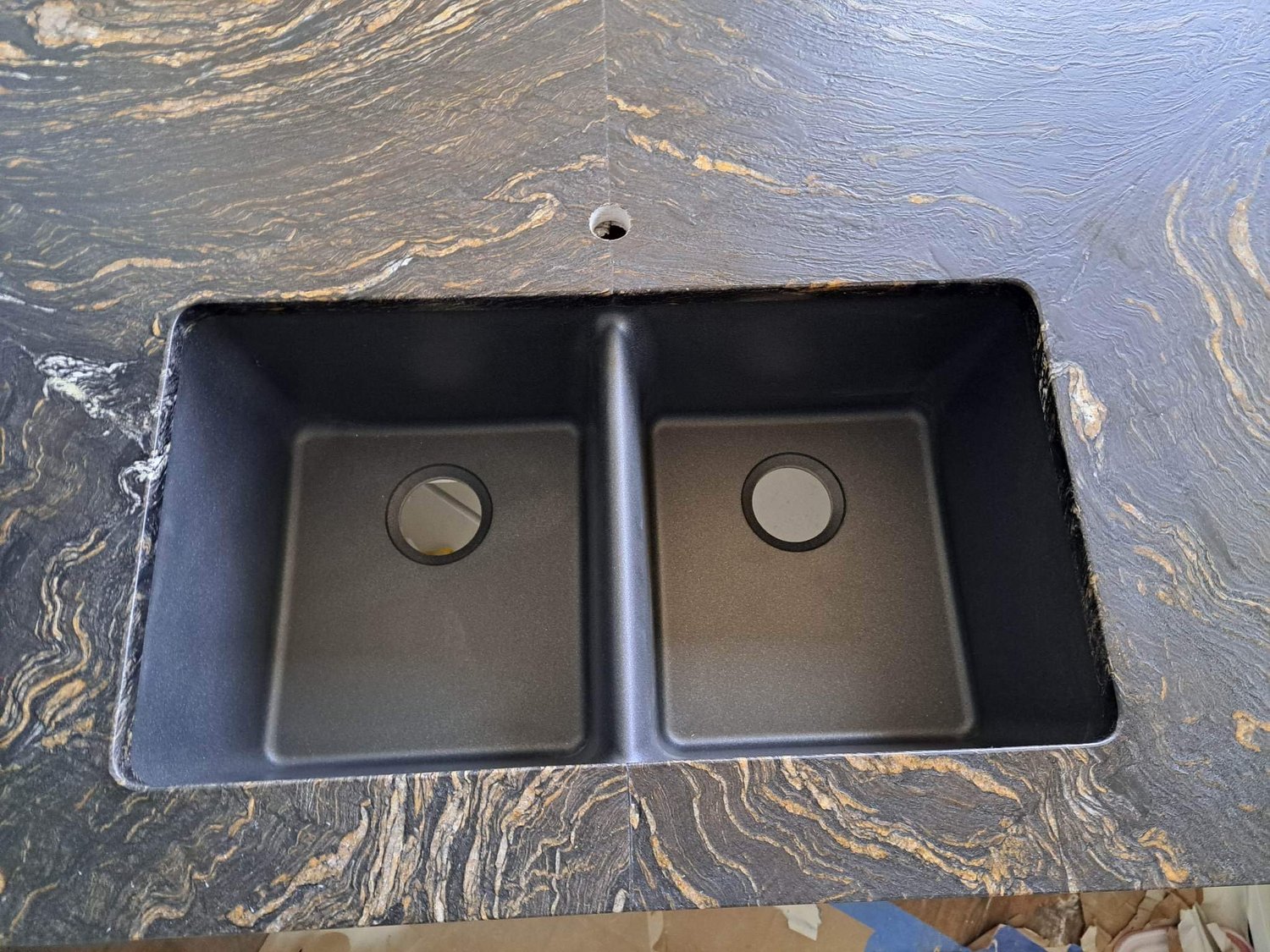 Close-up of a double-bowl stainless sink set into veined stone