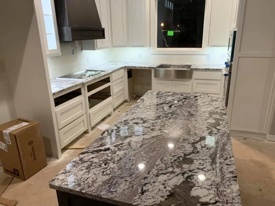 Light-toned granite island with a live, curved edge profile in an open kitchen