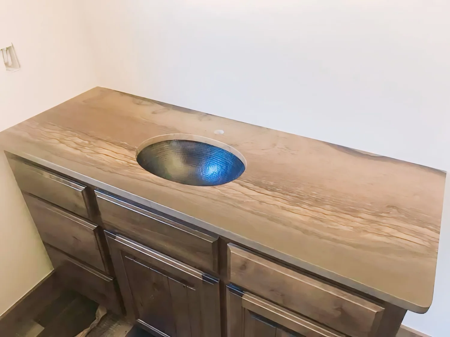 Stone vanity top with a round undermount sink and dark cabinet