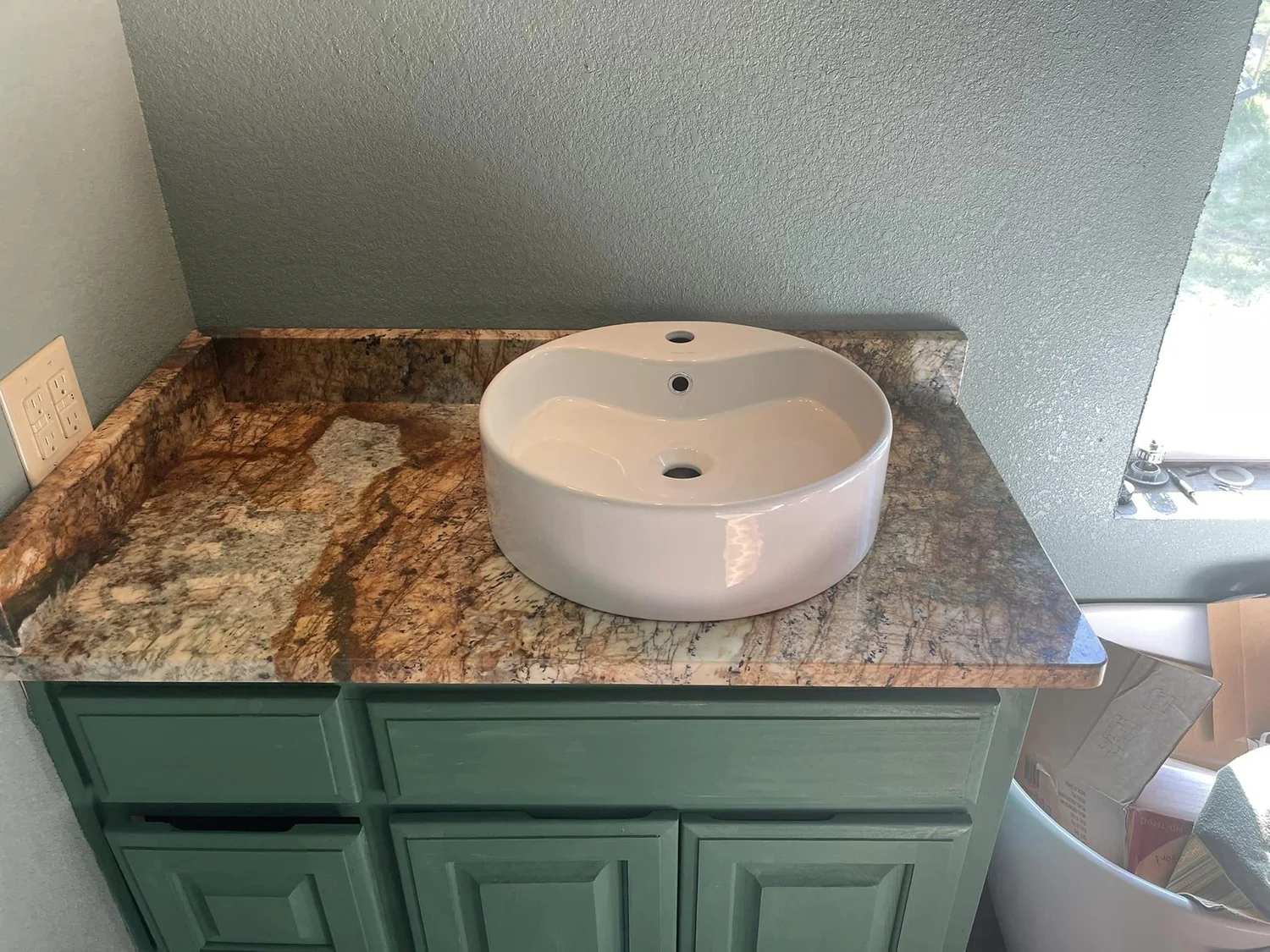 Granite vanity top with a white vessel sink on a painted bathroom cabinet