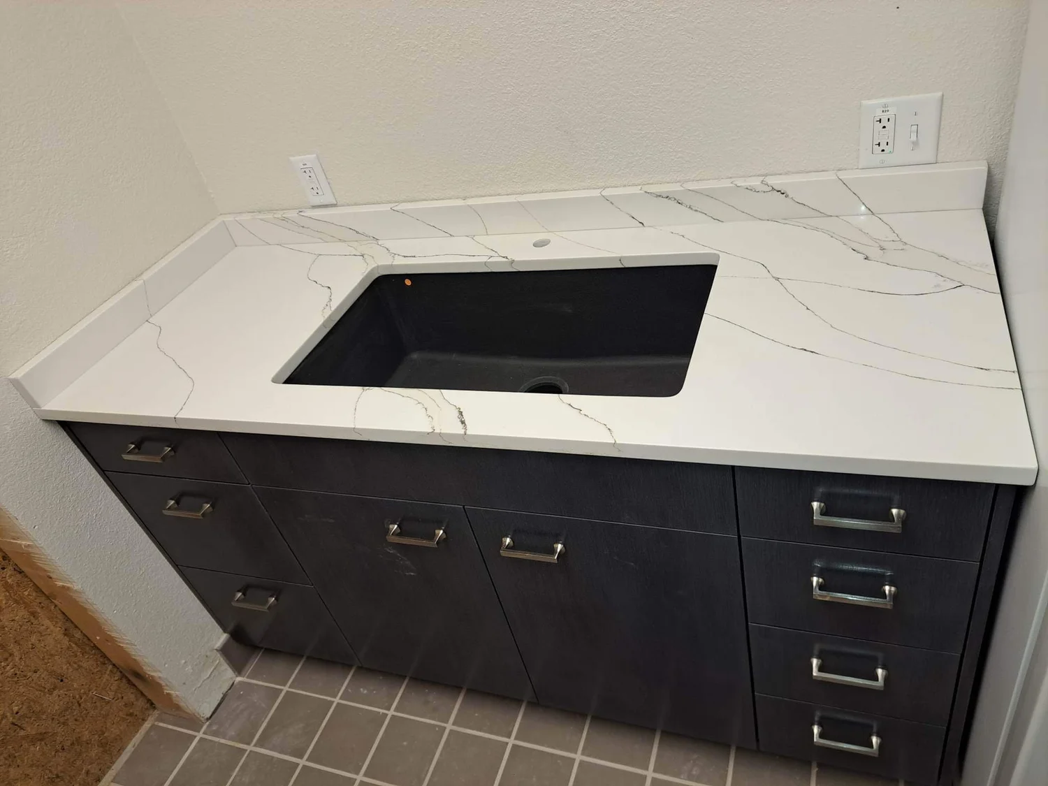 Marble-look quartz countertop over dark stained cabinetry with a cooktop