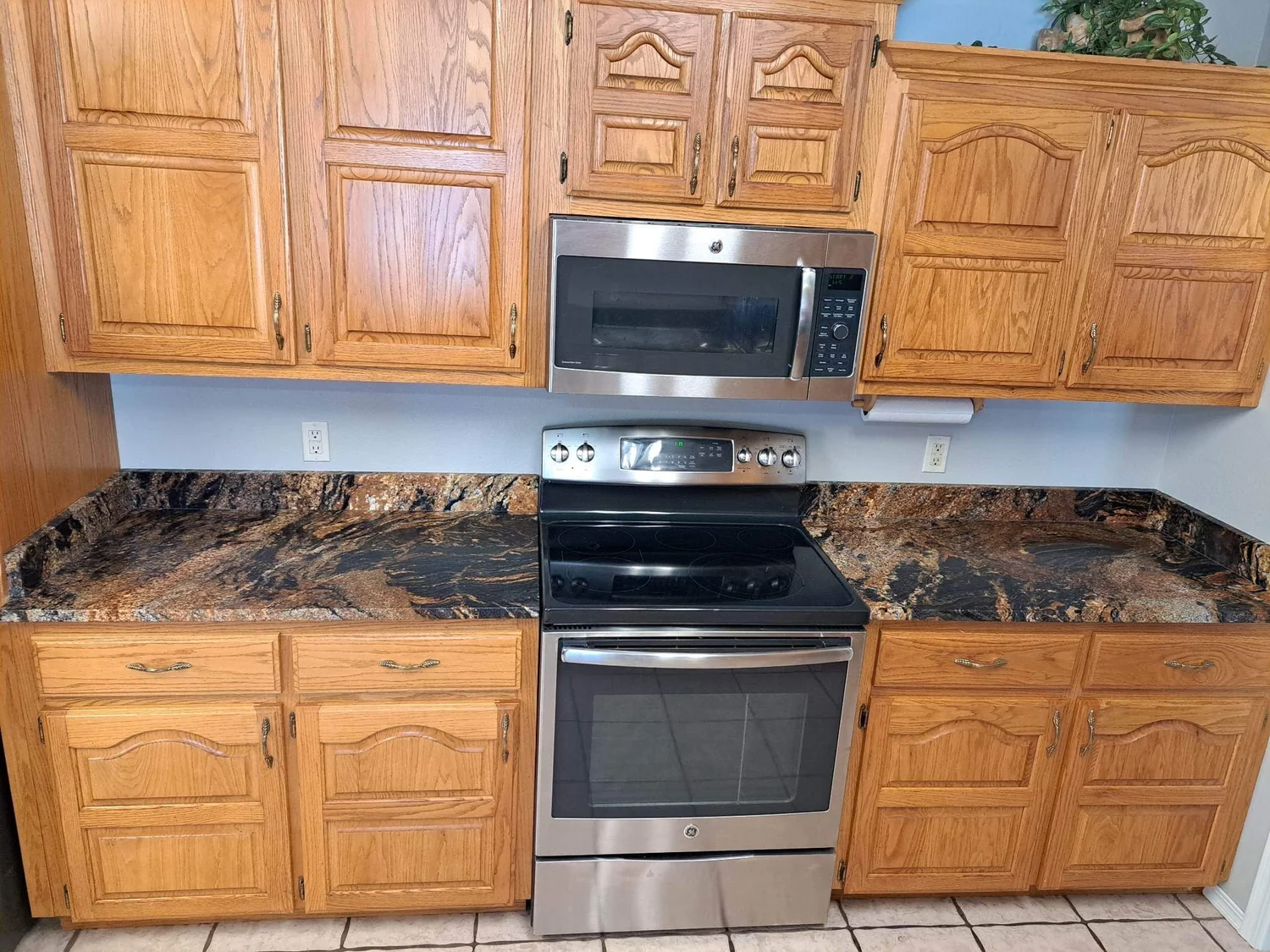Granite countertops beside a stainless wall oven and oak cabinets