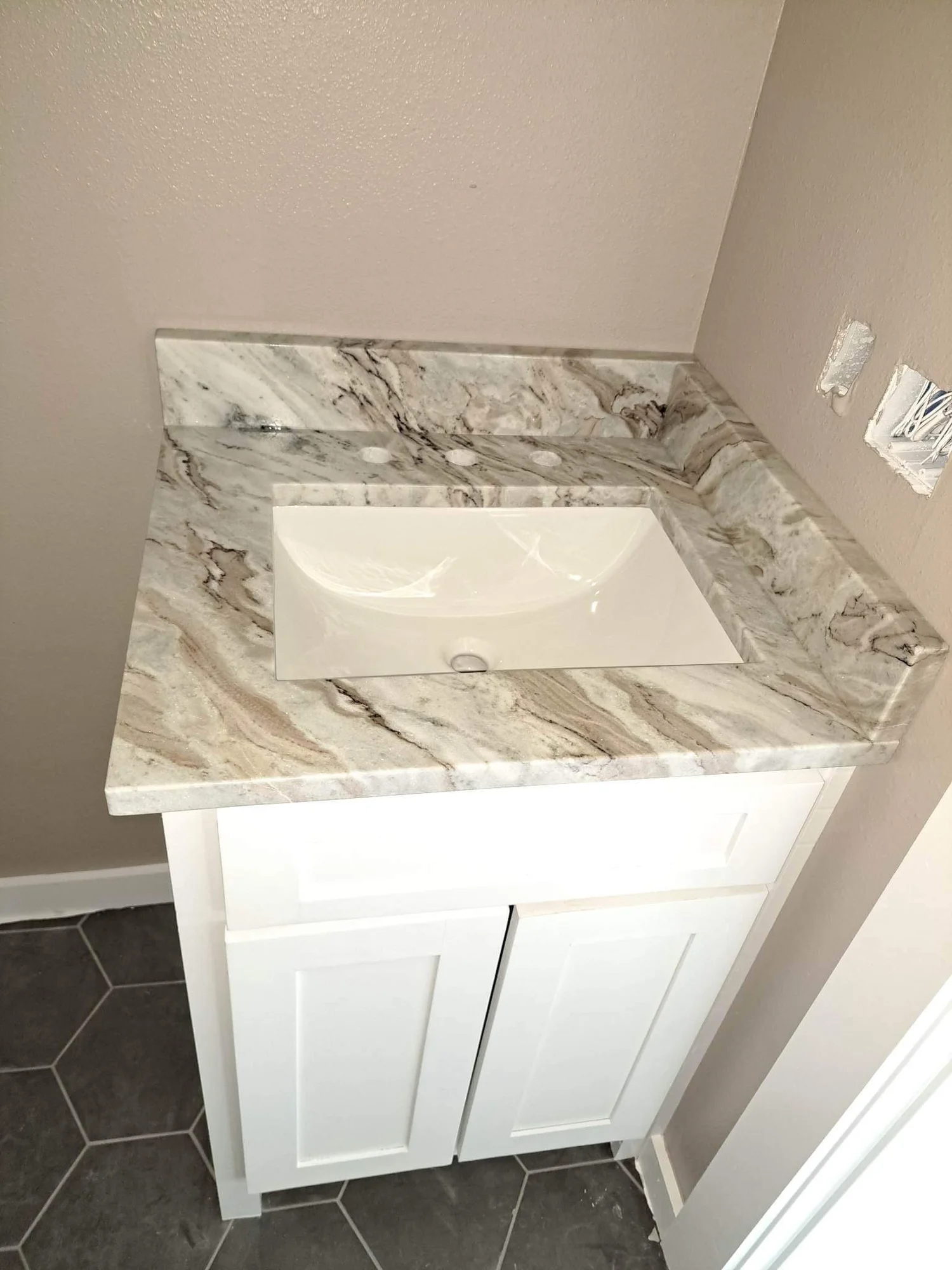 Marble-look stone vanity top with an undermount sink in a tiled bathroom