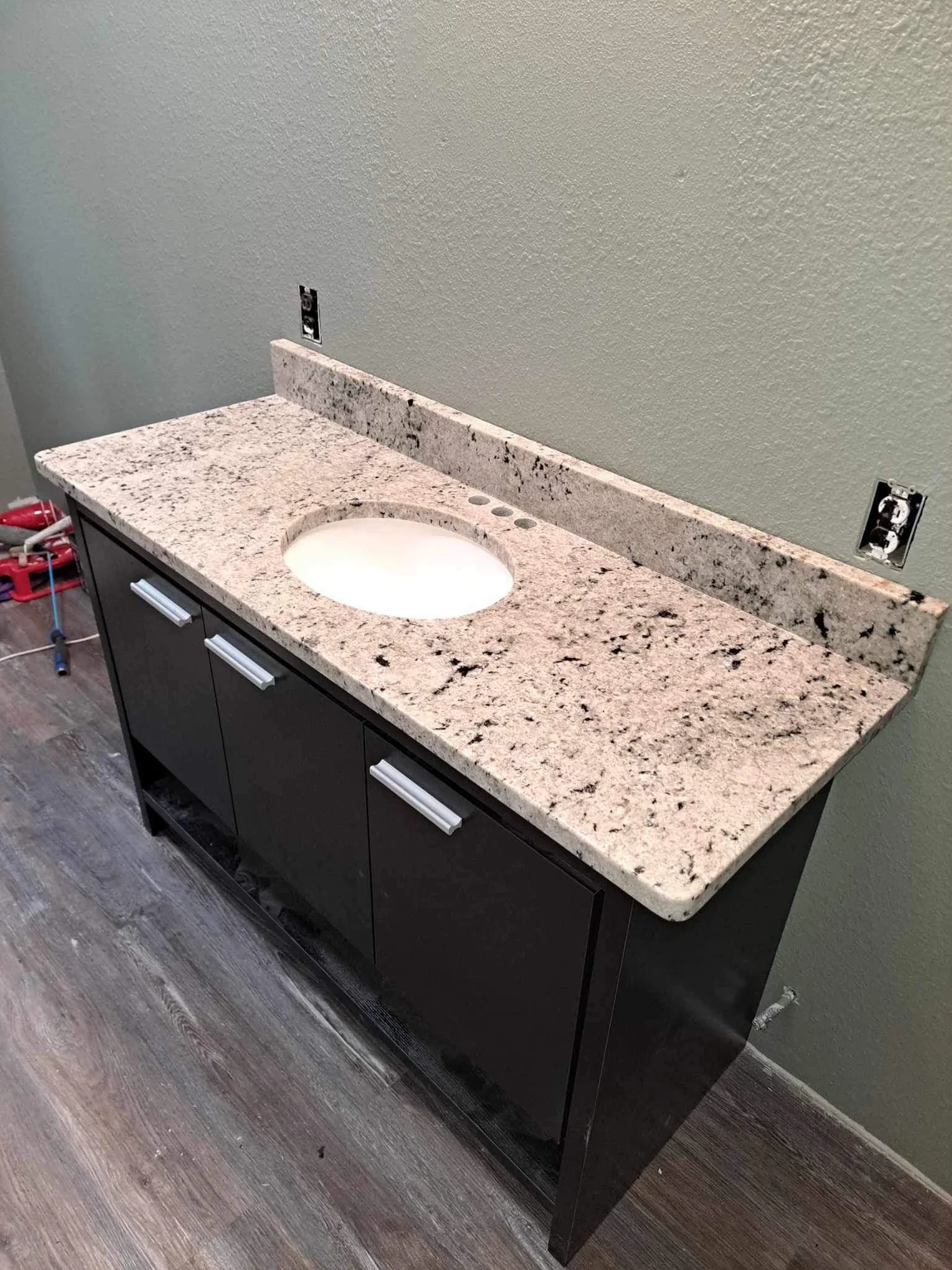 Granite vanity top with an oval undermount sink on a dark bathroom cabinet