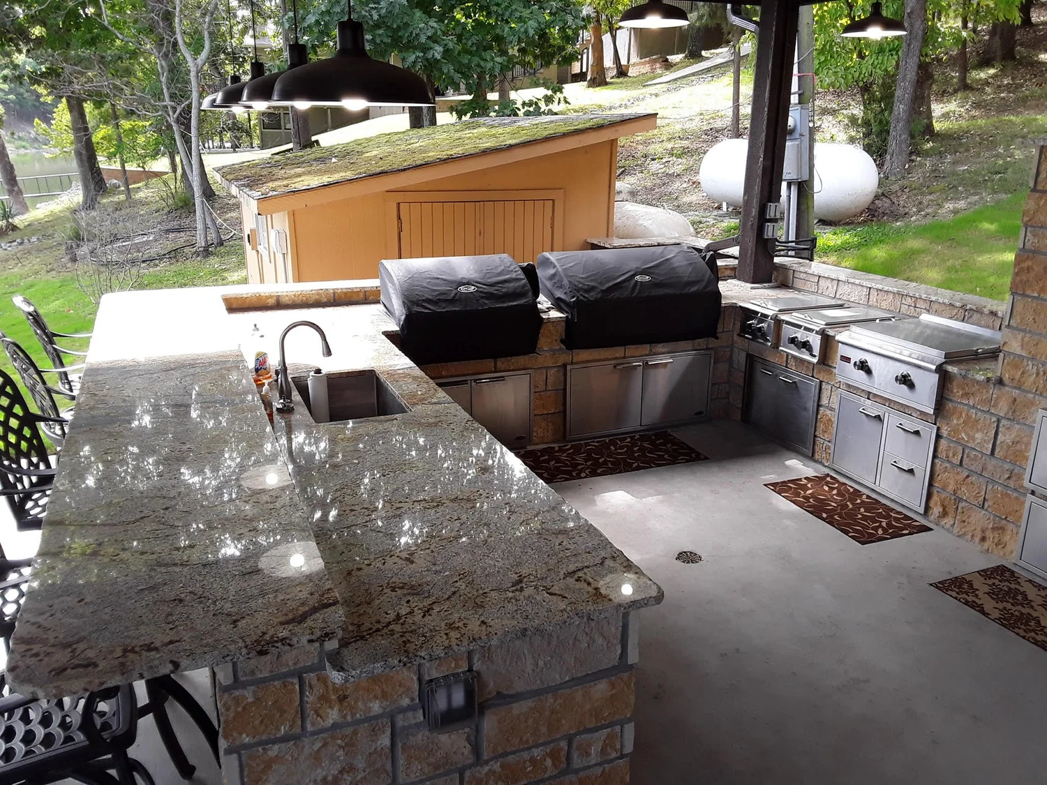 Outdoor kitchen with stone countertop, built-in grill and stainless doors