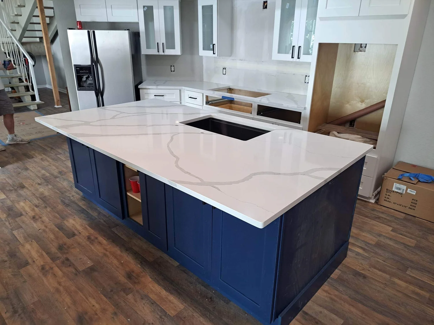 Navy blue kitchen island topped with white quartz in a new build