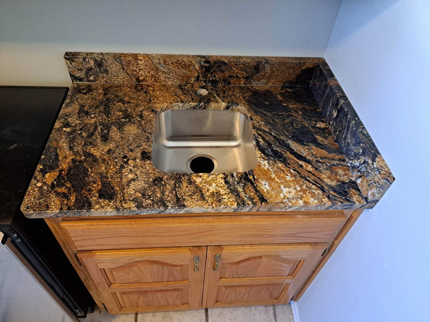 Stone vanity top with an oval undermount sink and brushed fixtures