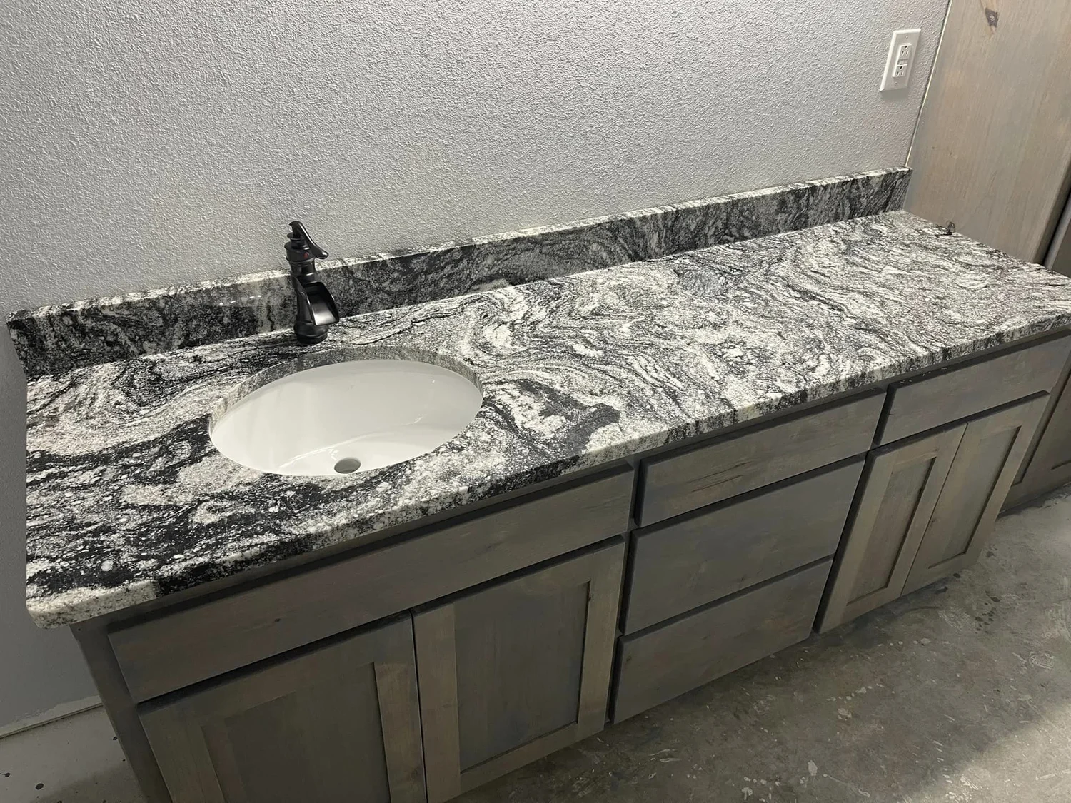 Marble-look vanity top with an undermount oval sink and gray cabinetry