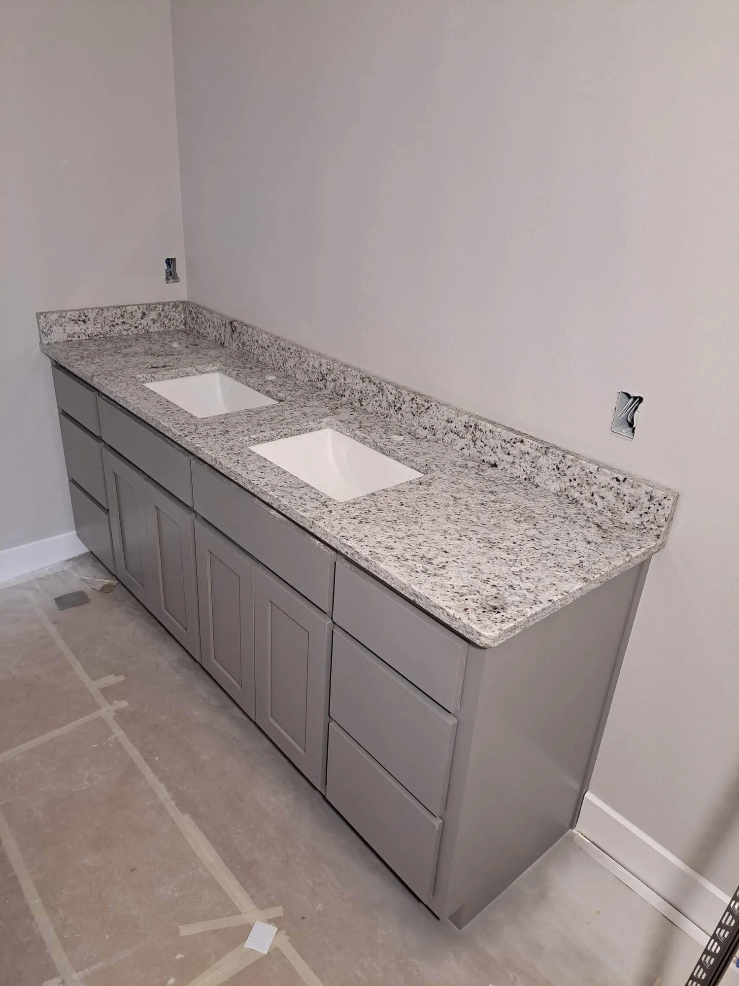 Granite vanity top on a white bathroom cabinet with a shower beyond