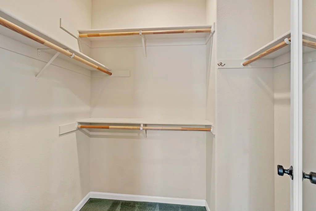 Empty closet with white shelves and hanging rods.