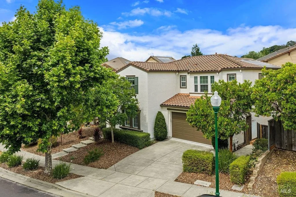 Front view of a sold house at 915 Colorado Blvd, Santa Rosa, CA, with a light green exterior, dark blue front door, two large windows, a small front yard with grass, bushes, and a large rock.