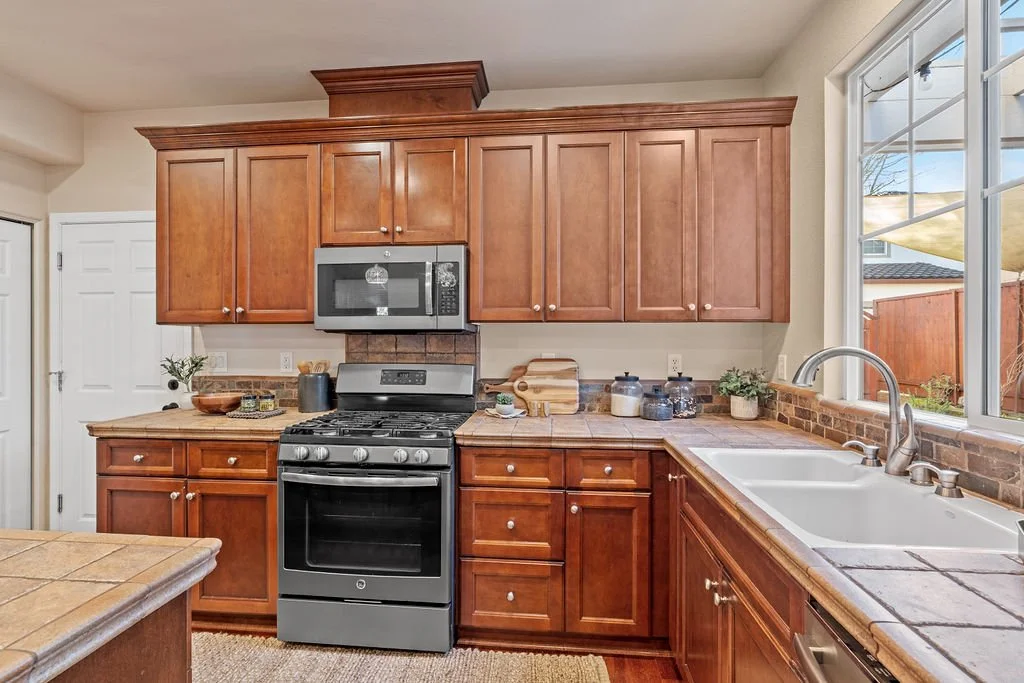 Kitchen with wooden cabinets, stainless steel microwave, oven, and a large window over the sink.