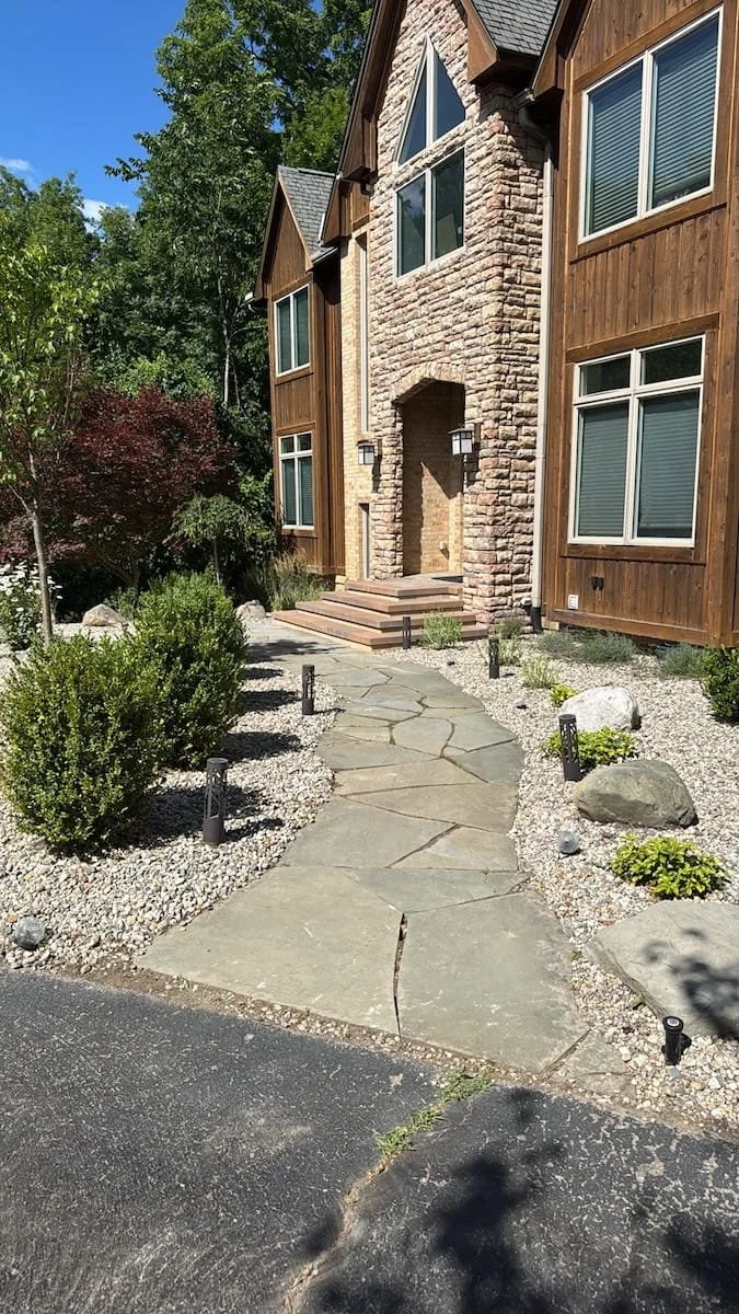 Winding flagstone walkway with path lighting leading from the driveway to a stone archway entry in Livonia, MI