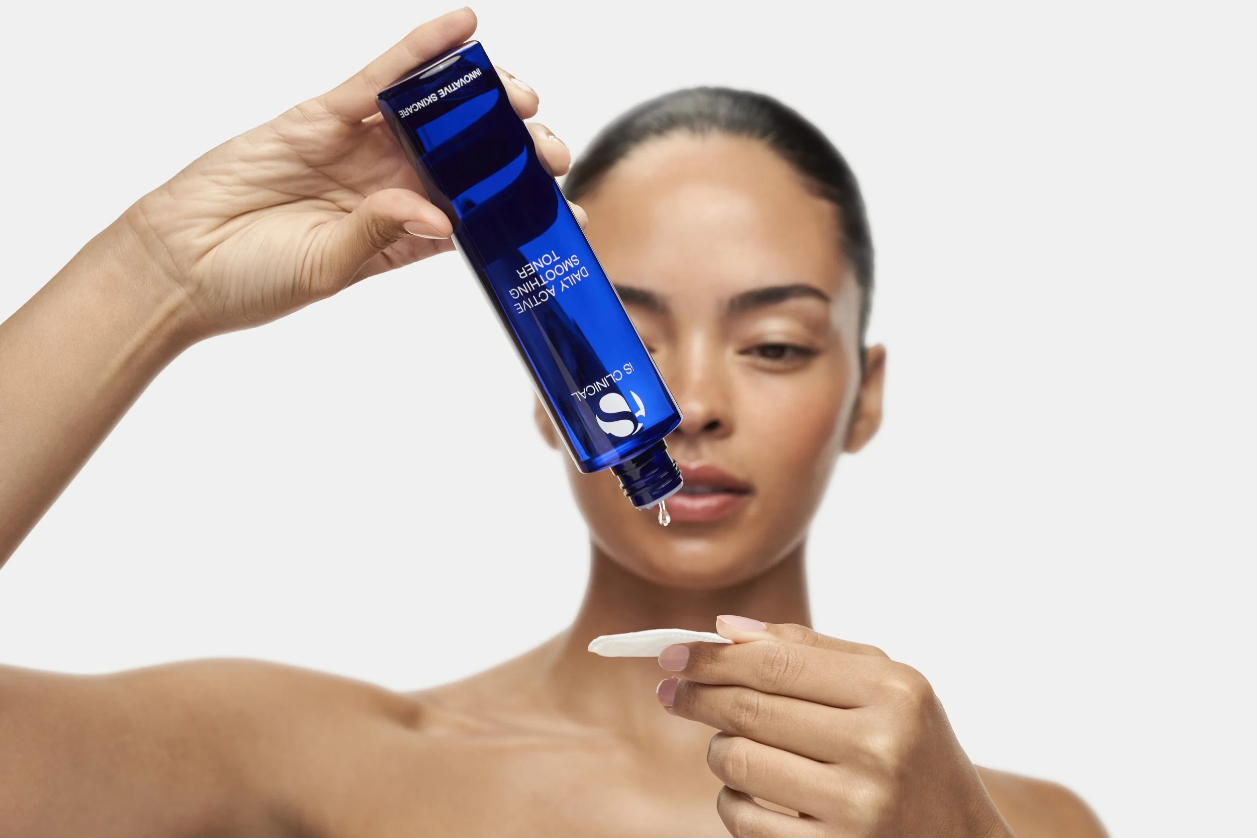Girl applying iS Clinical Daily Active Smoothing toner to a cotton pad