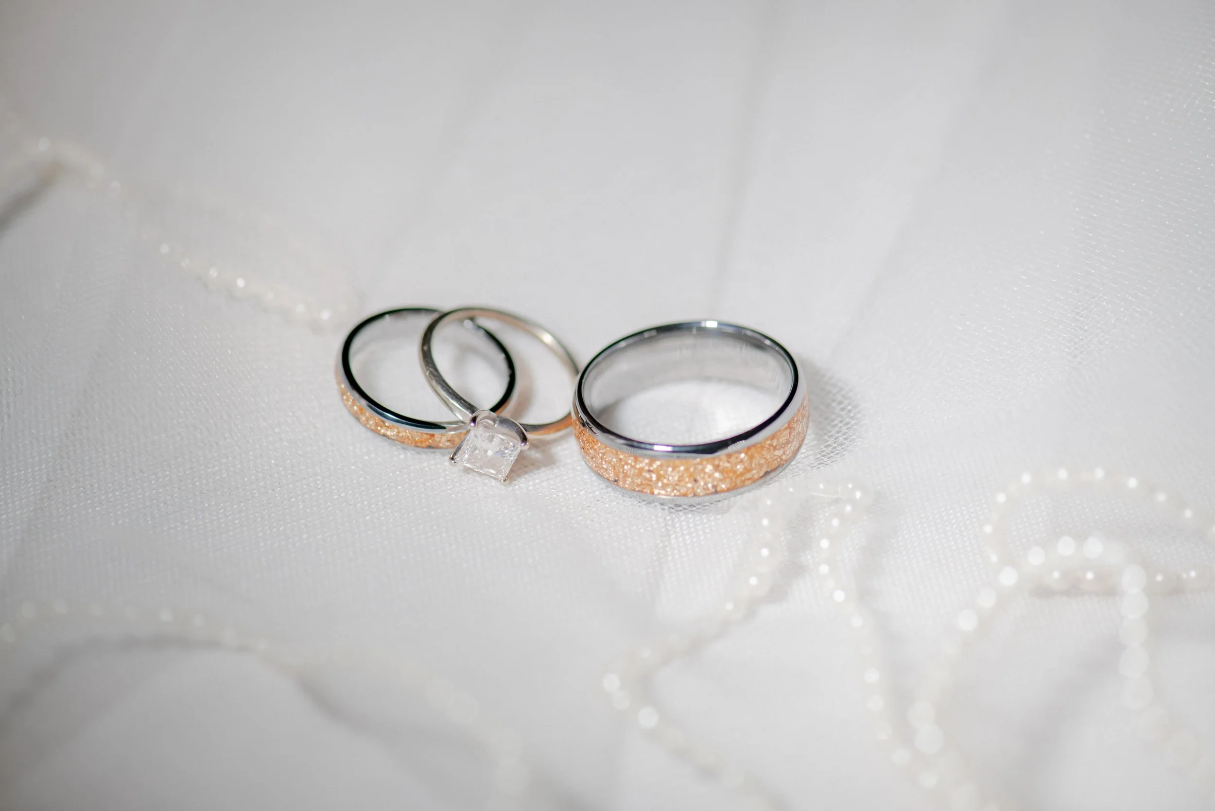 A group of people participating in an outdoor water activity, with a woman in the center raising her hands with water splashing around her, on a sunny day with a blue sky and green landscape in the background.