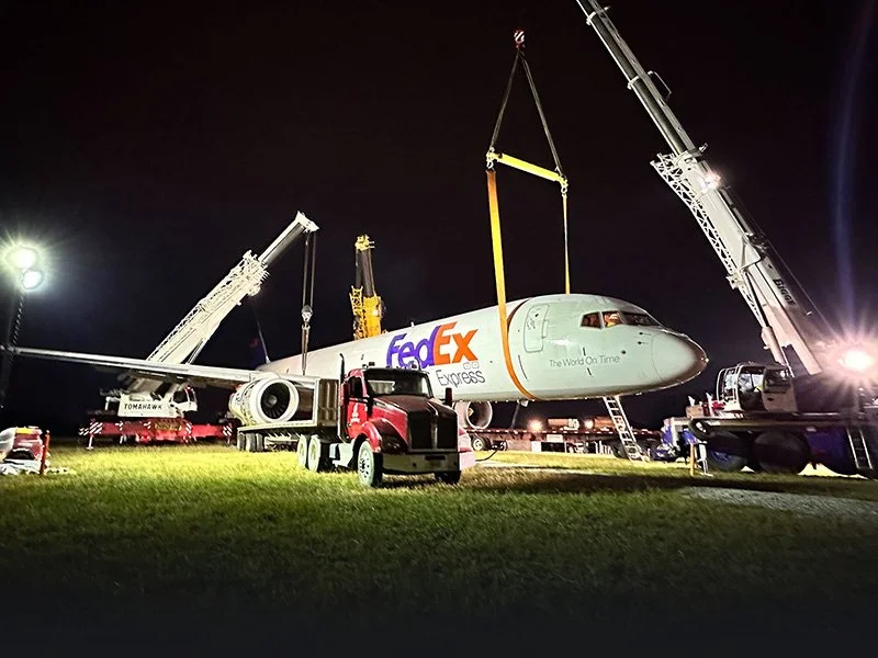 FedEx Express airplane being transported or moved at night using crane equipment.
