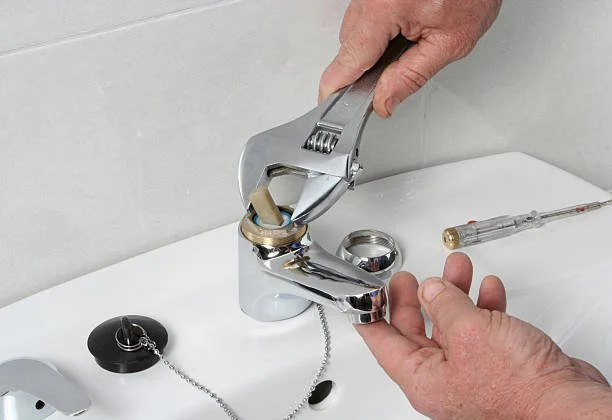 Person using pliers to remove a sink stopper from a bathroom sink.
