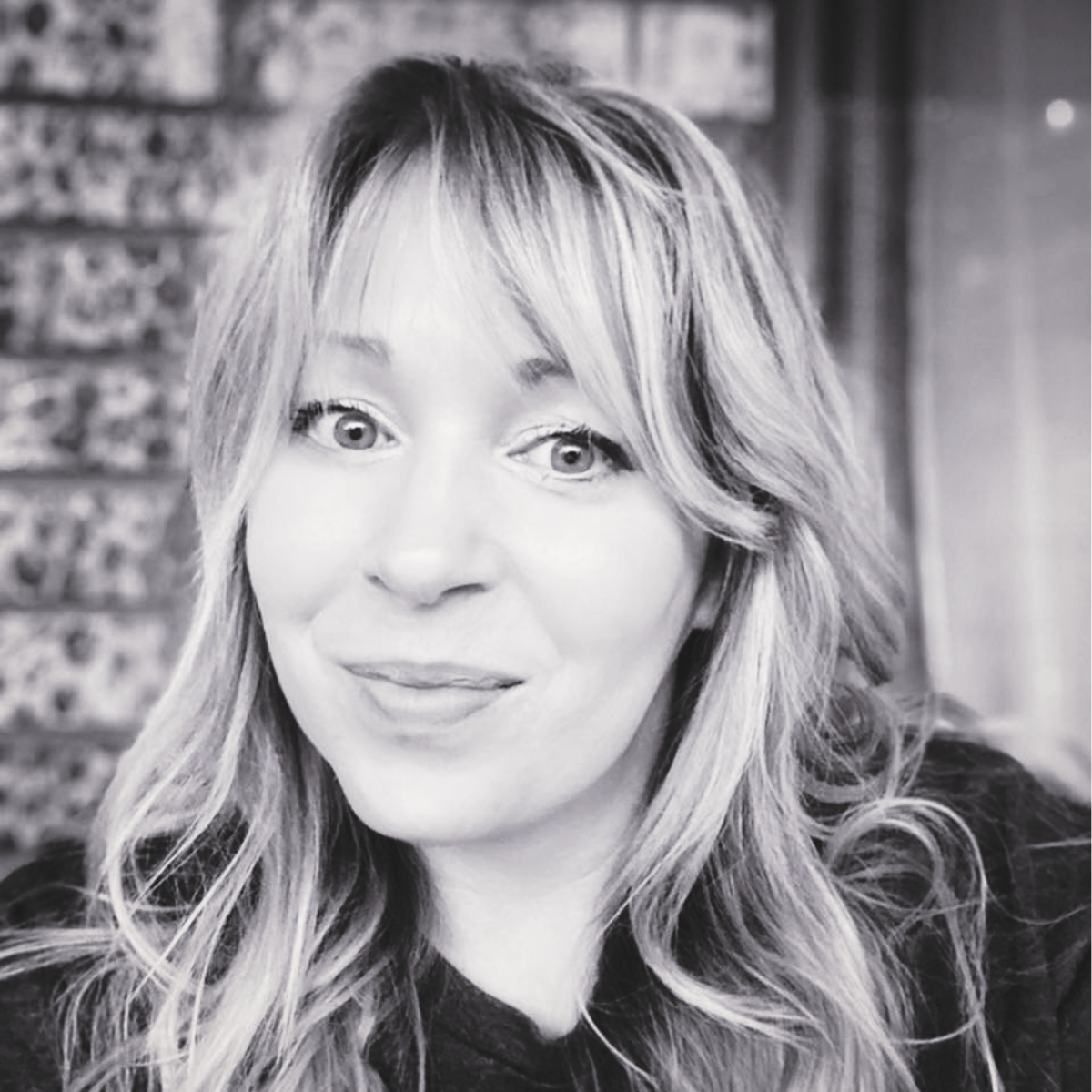 Black and white close-up photo of Debbie Long with wavy hair, smiling slightly, looking directly at the camera.