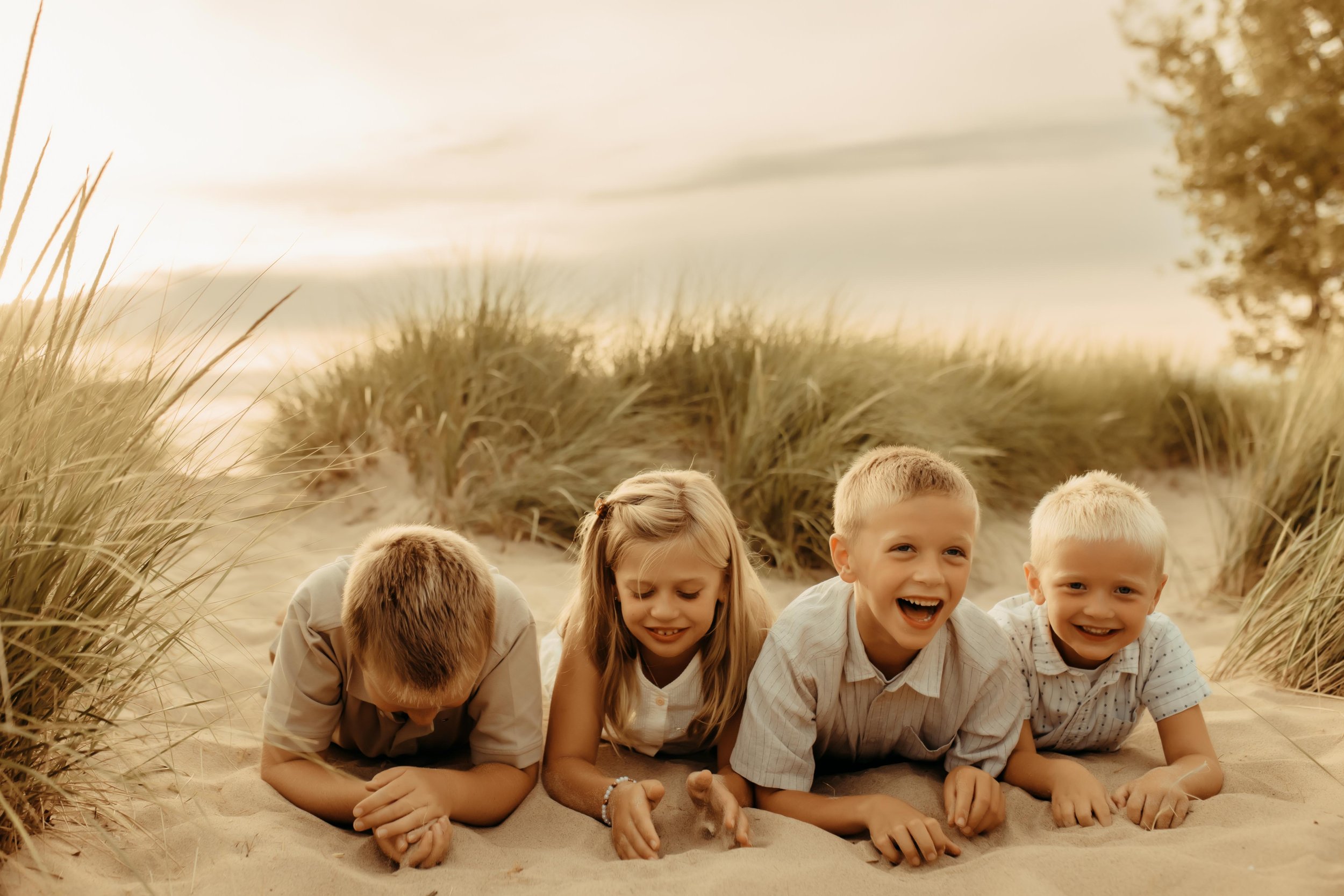 Kids laughing in the sand at Oval Beach in Saugatuck Michigan during photography session