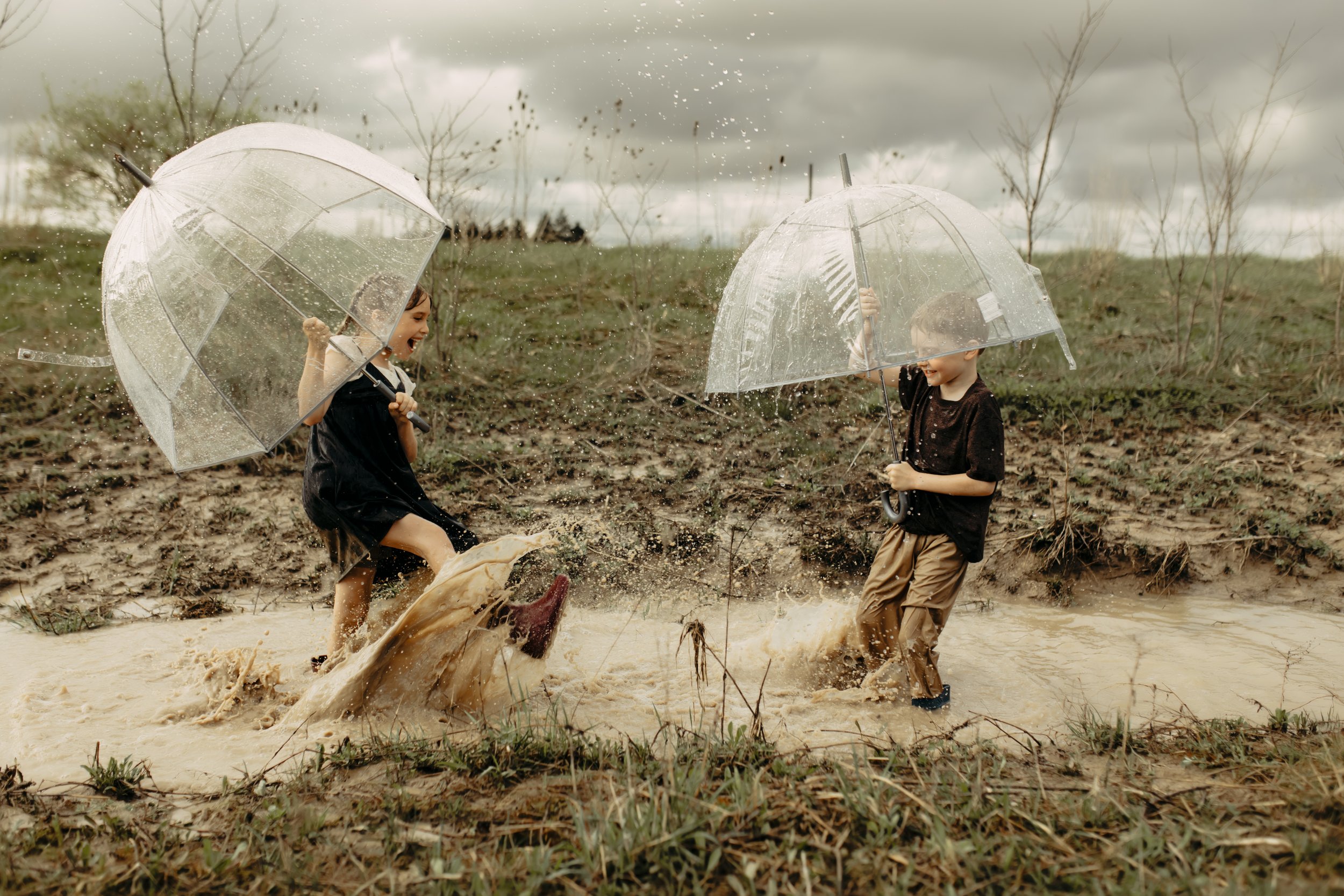 Family photography session in Hudsonville, Michigan with kids splashing in puddles during documentary session in west michigan