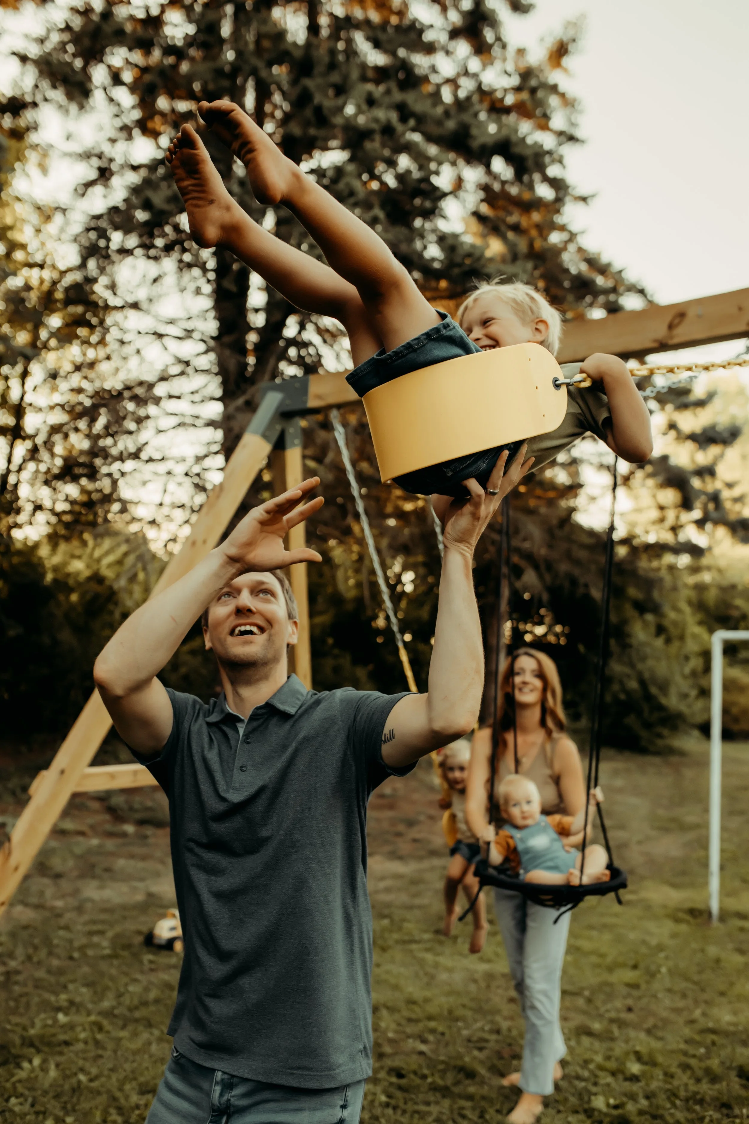 Parents pushing kids on swings in backyard during a documentary photography session in Michigan