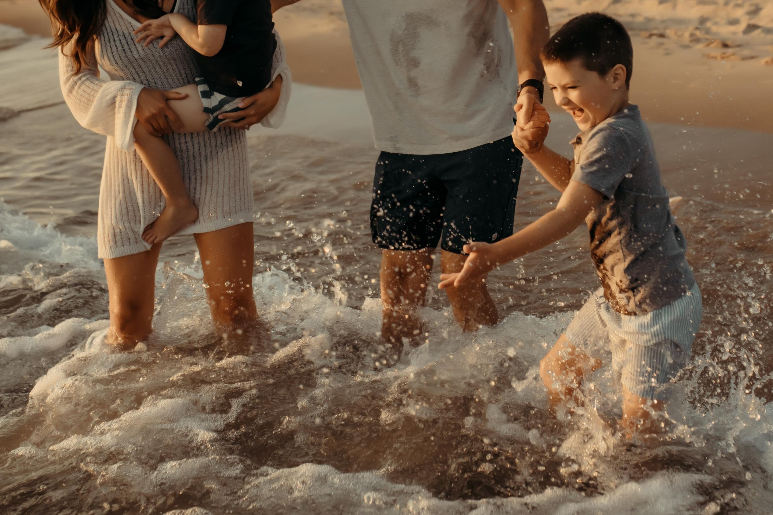 family laughing and splashing in the waves at lake michigan