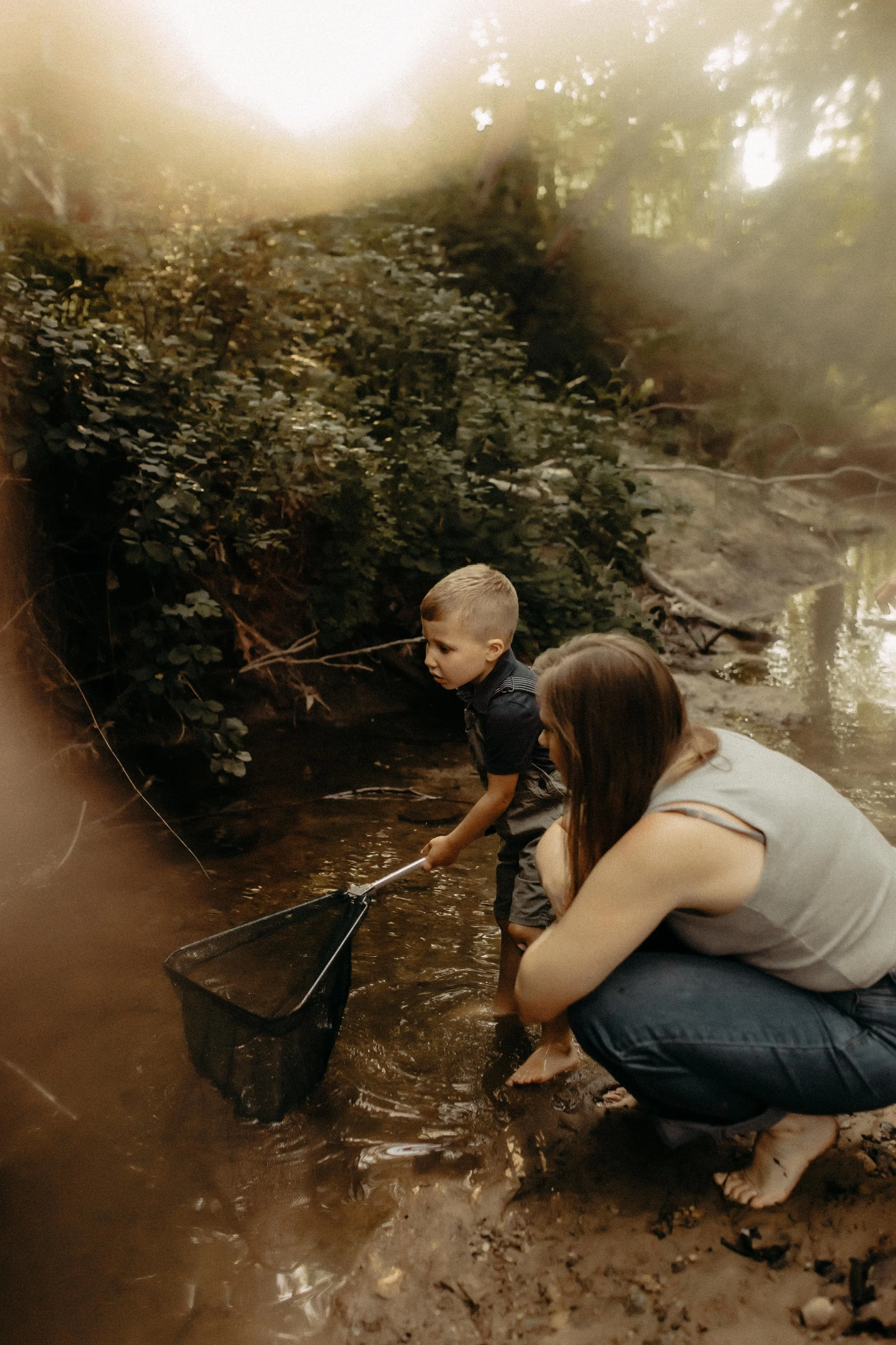 Family tries to catch fish with a net in the creek during family photo session