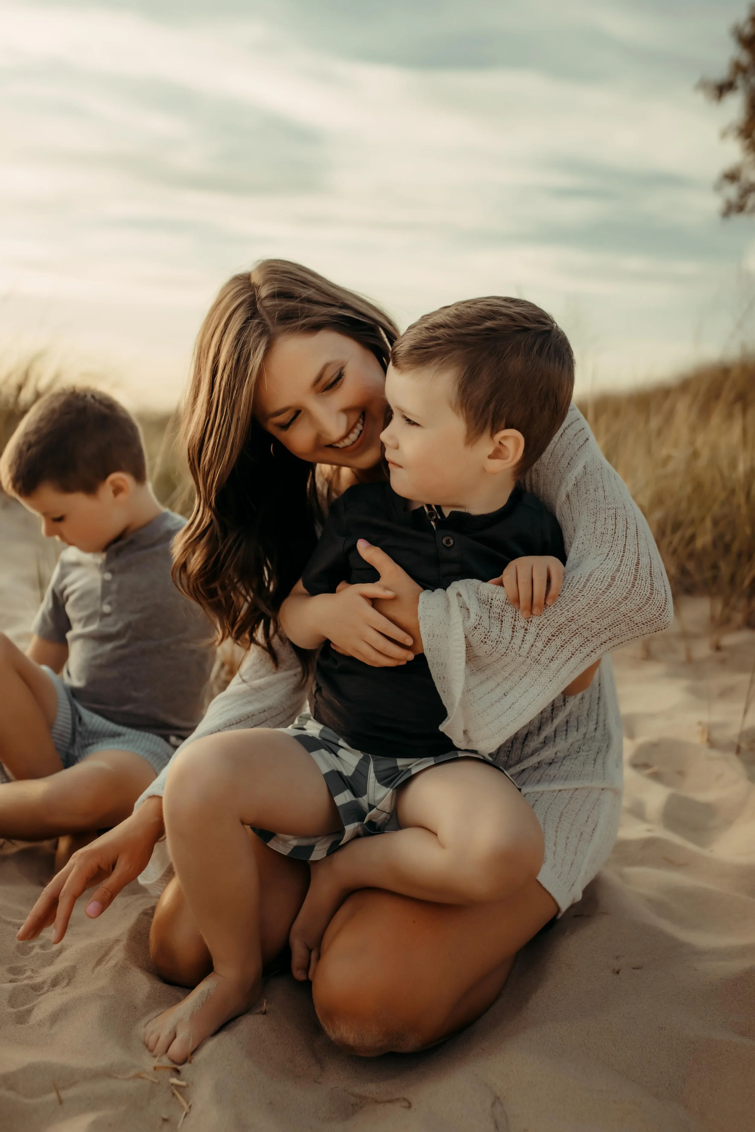 family snuggling on the sand dunes at Grand Haven, Michigan beach