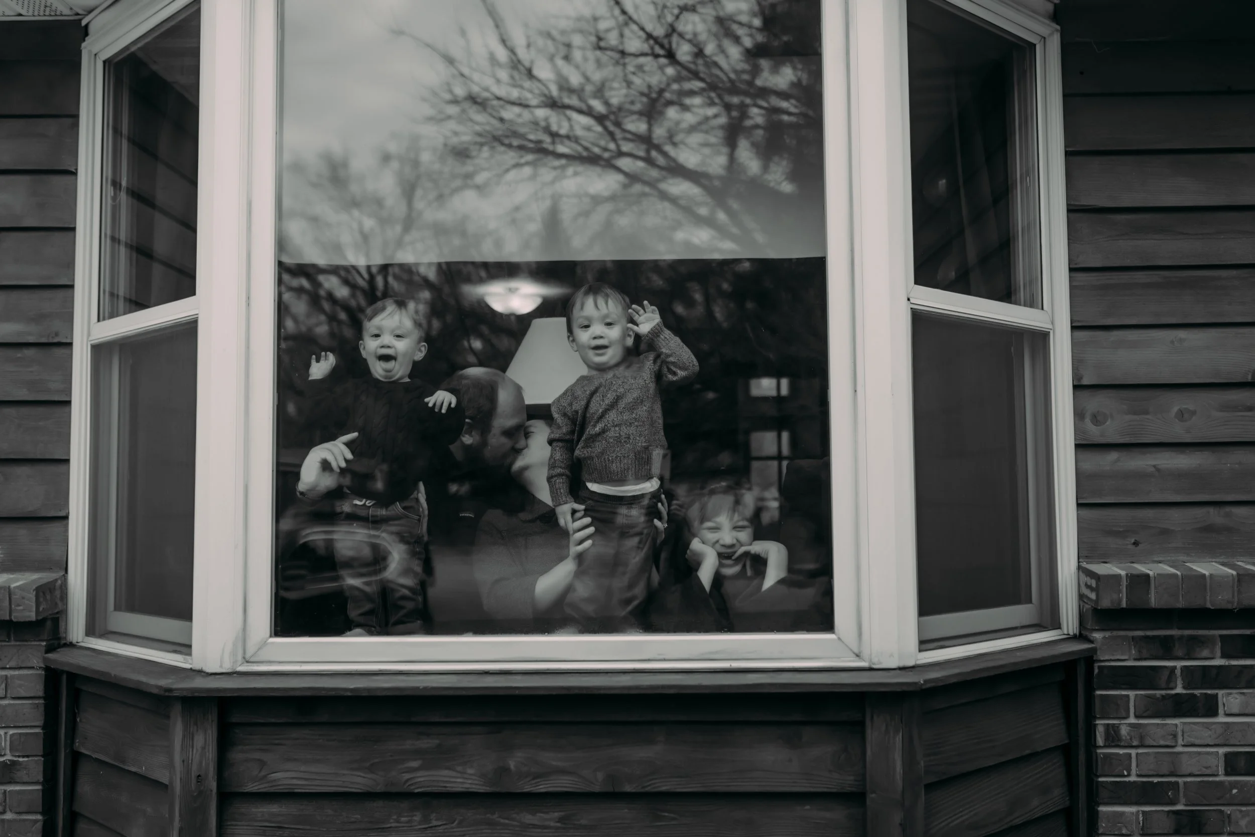 Family looking out of their window at the home in Grand Rapids, Michigan during an in-home documentary family photography session