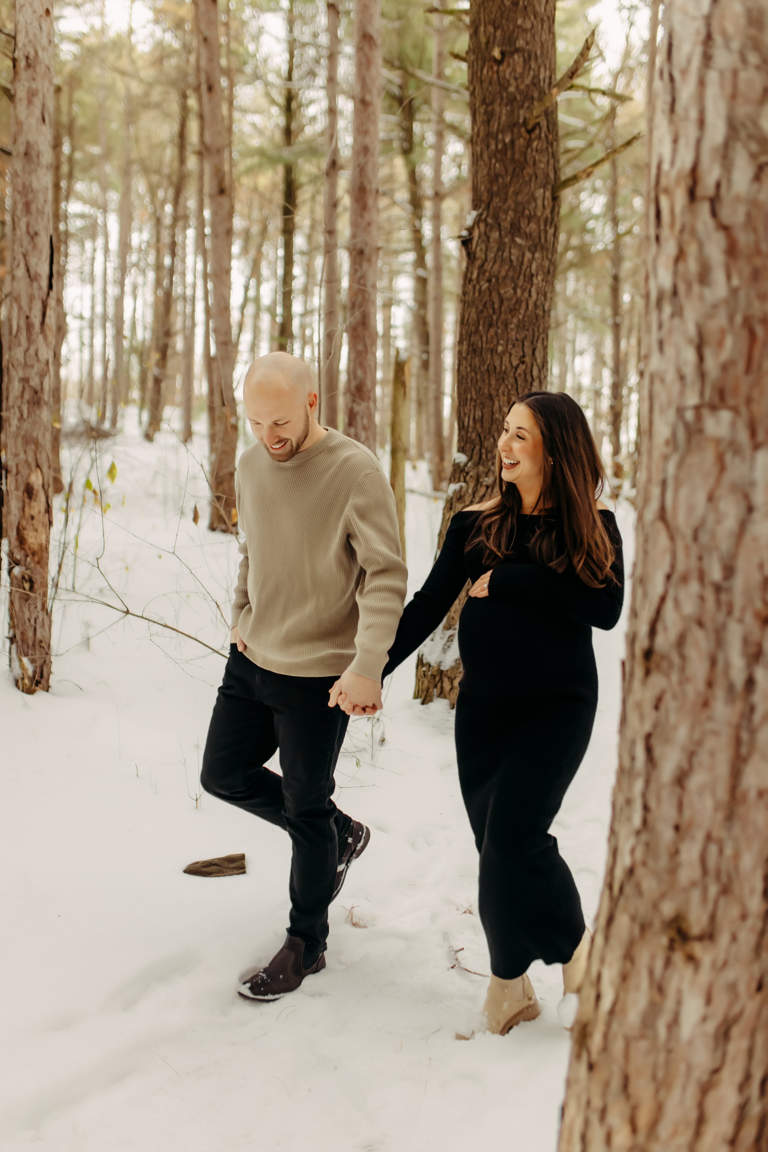 pregnant mom and husband at provin trails for photography session walking hand in hand in Grand Rapids, Michigan