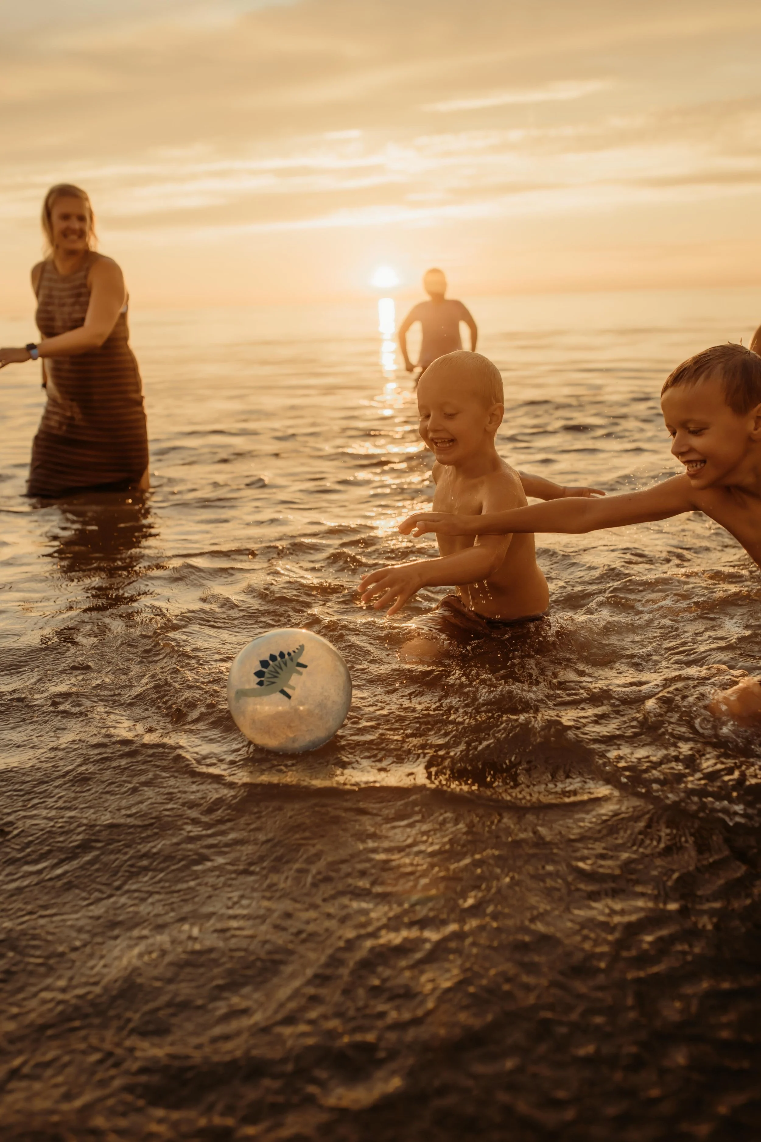 Family laughing and playing in the water at the beach in Saugatuck, Michigan during photography session
