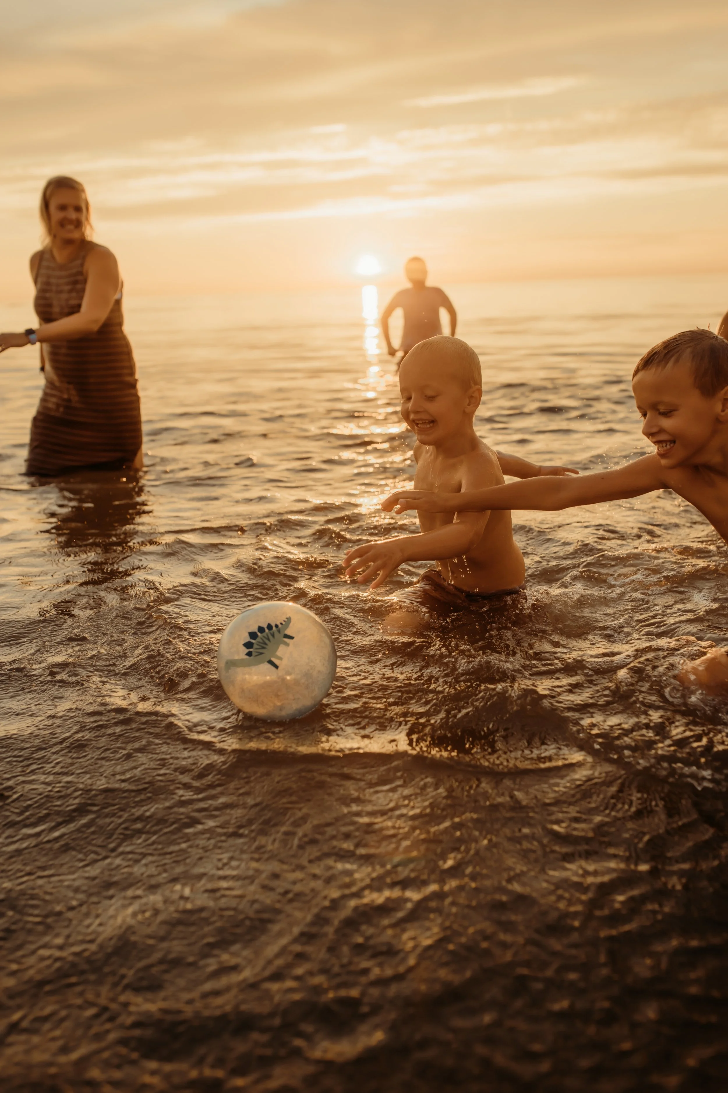 Family laughing and playing in Lake Michigan at sunset in Holland, Michigan