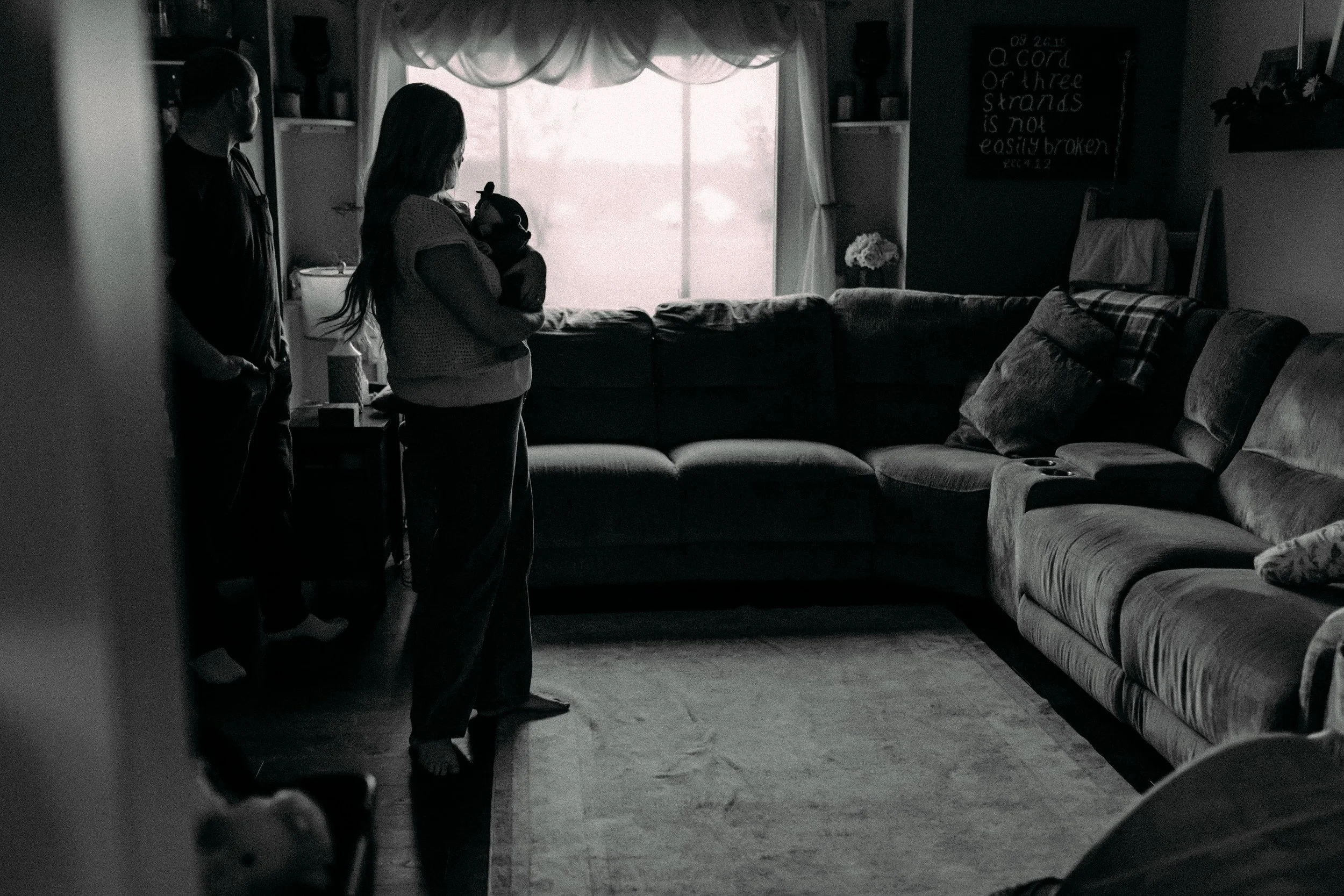 mom and dad with newborn in their home during documentary photography session in grand rapids, michigan