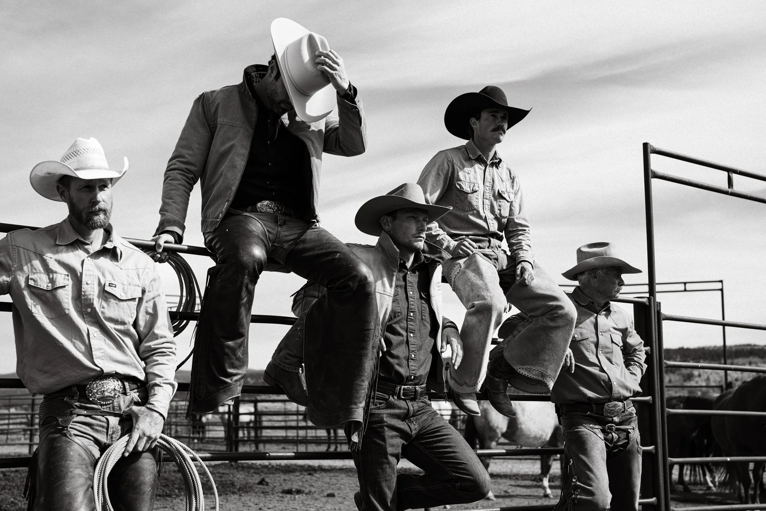 five cowboys sitting on a fence