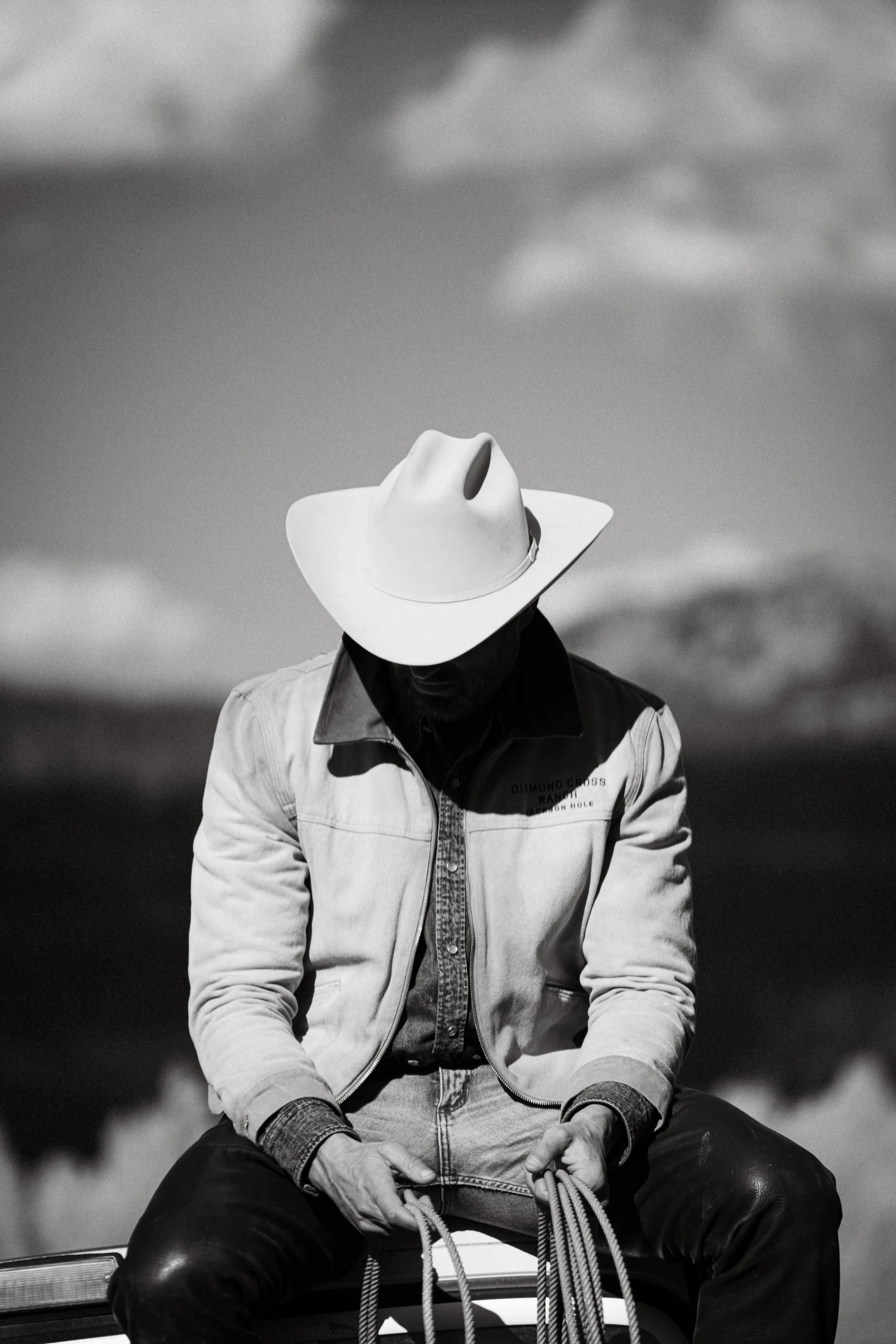 black and white photograph of a cowboy sitting with rope in his hand