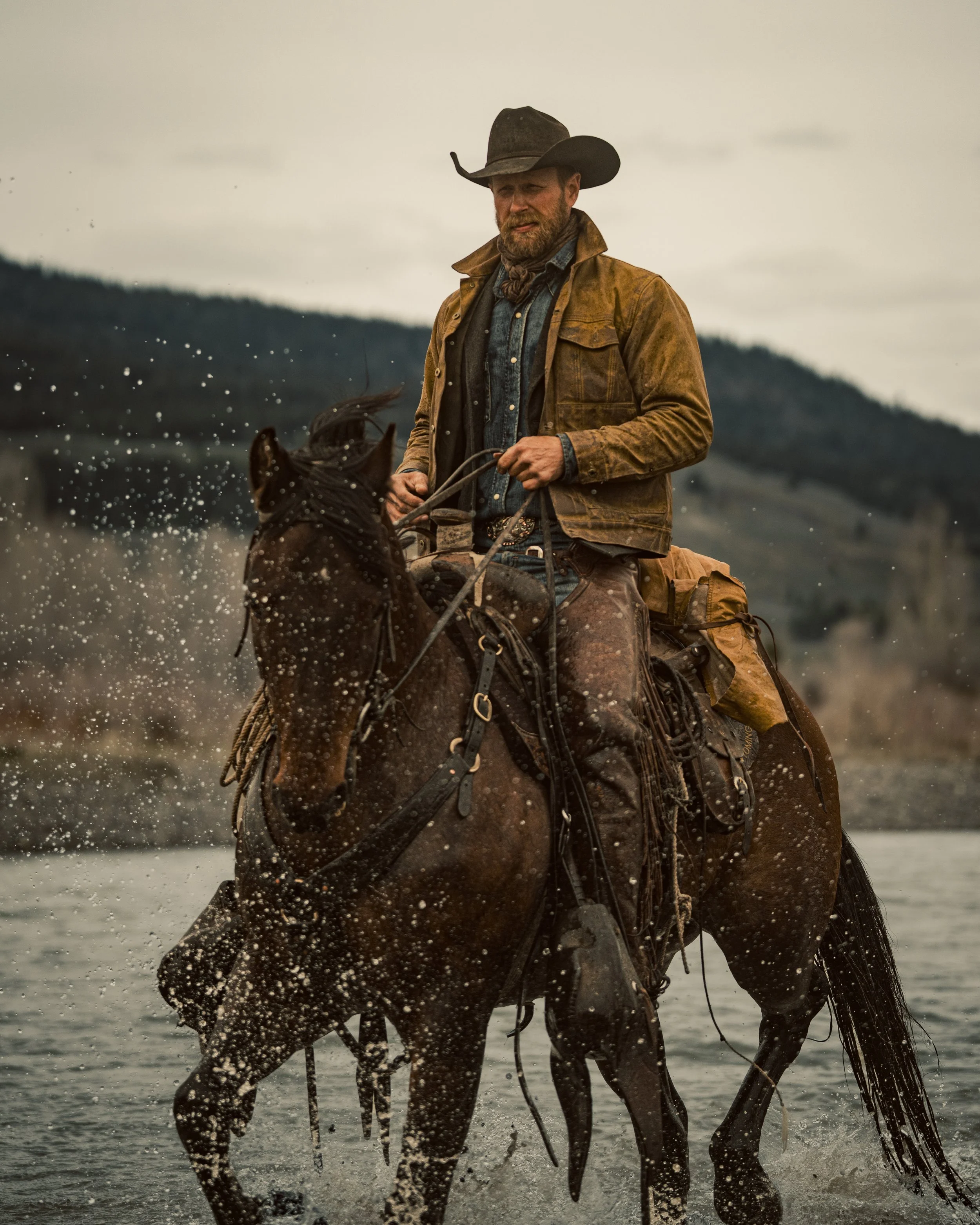 cowboy riding horse through river