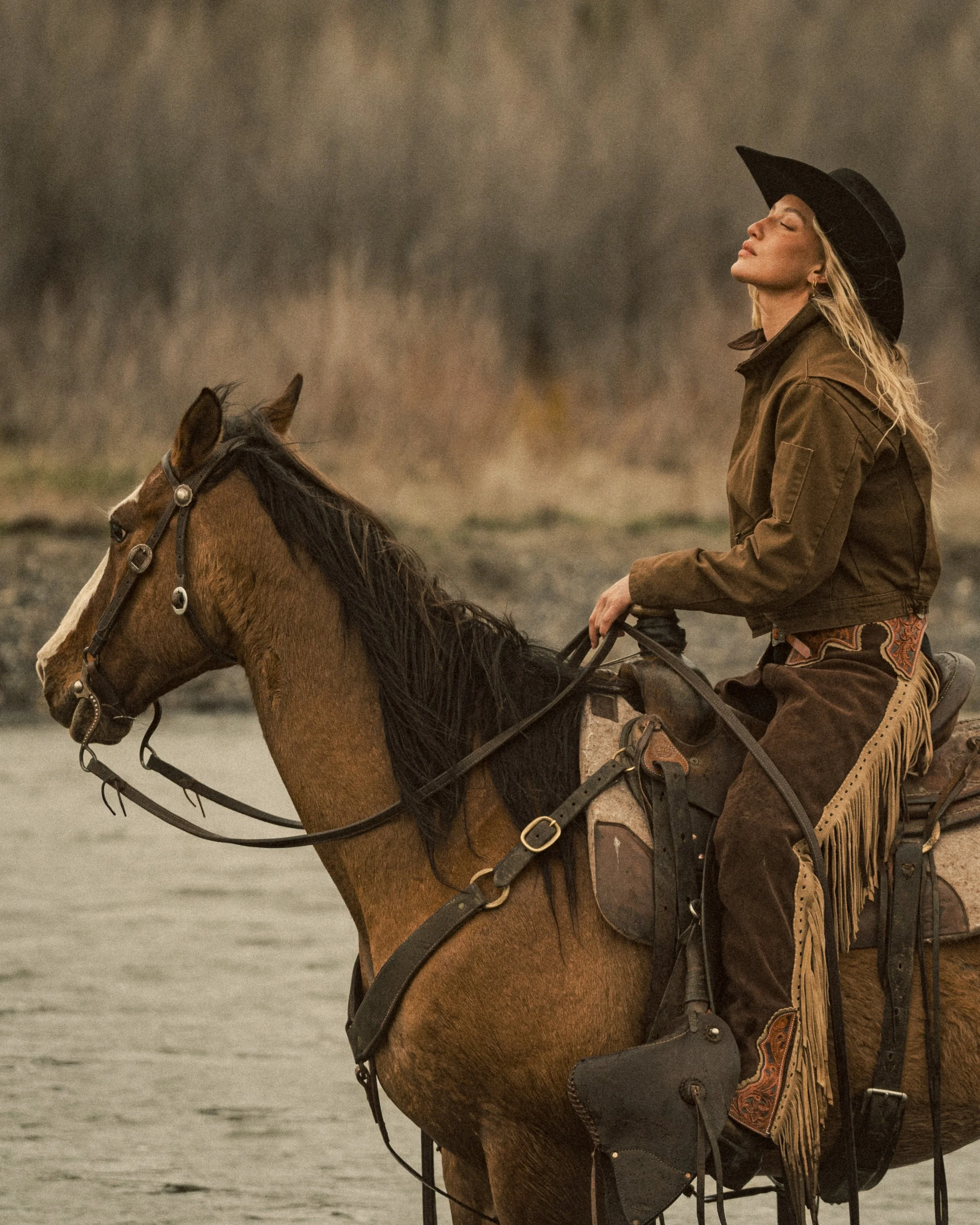 cowgirl riding horse in river with eyes closed