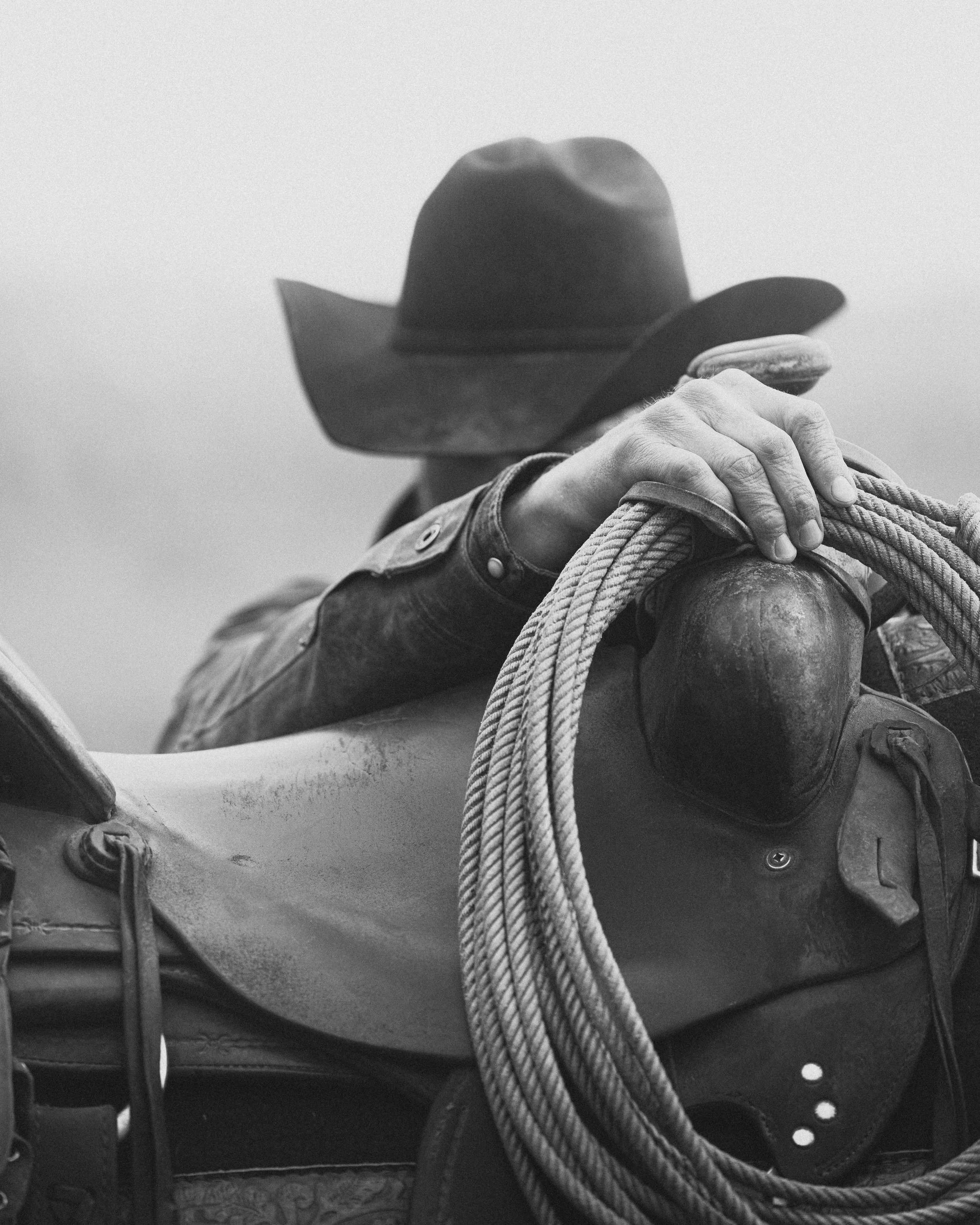 cowboy putting rope on side of saddle