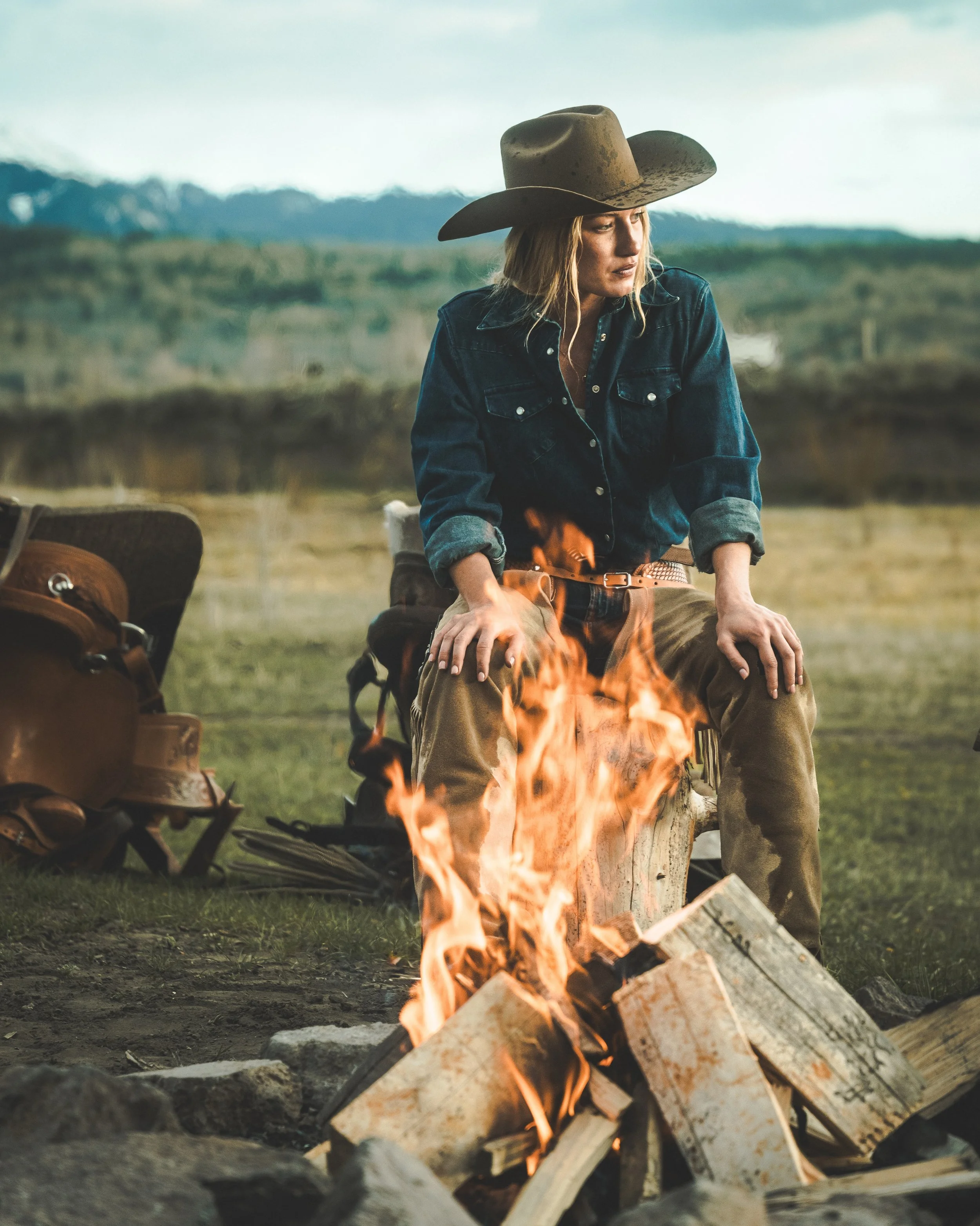 cowgirl sitting in front of camp fire