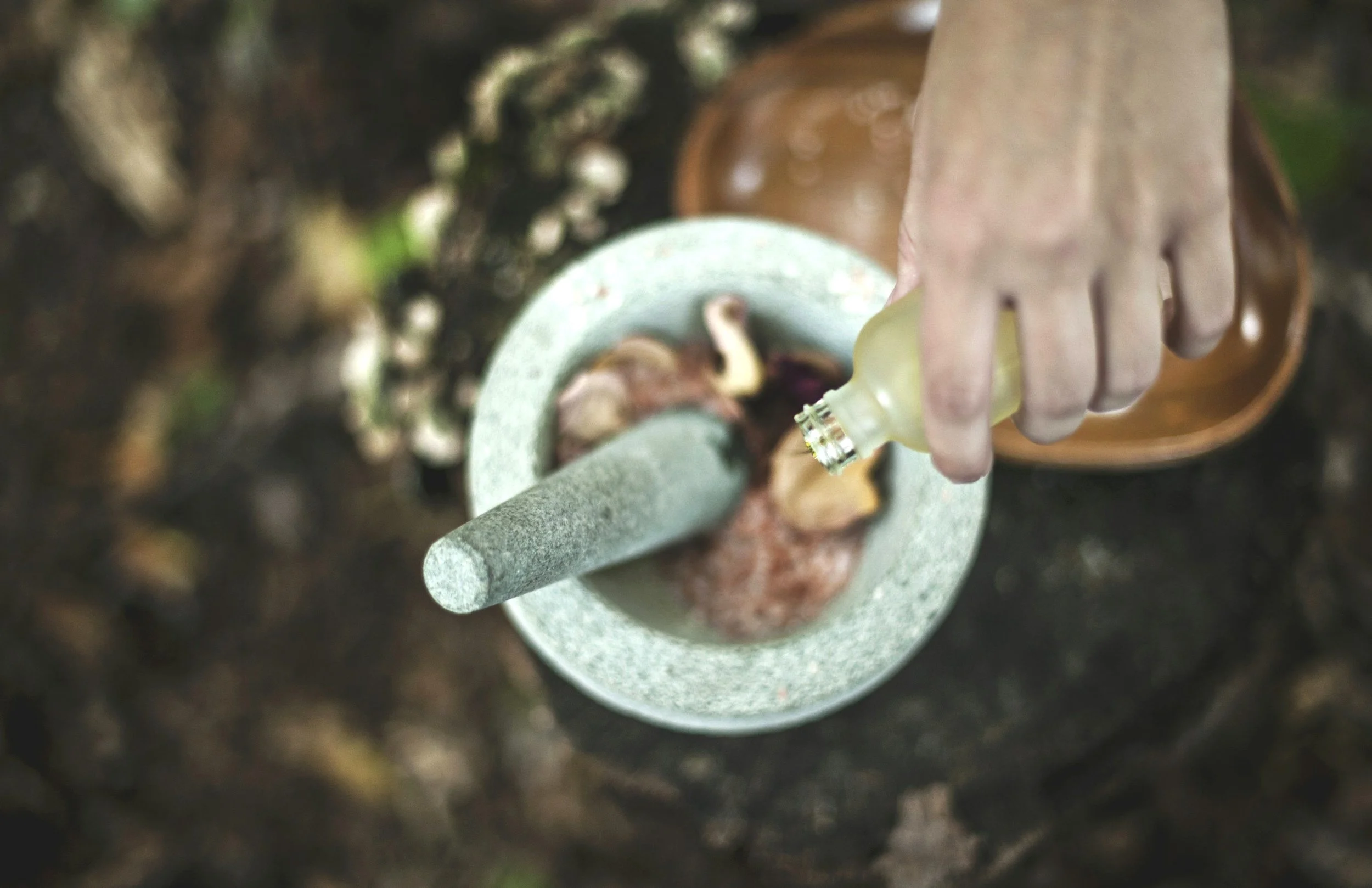 A person grinding a piece of wood with a grinding stone, using a small brush to apply oil from a small bottle.