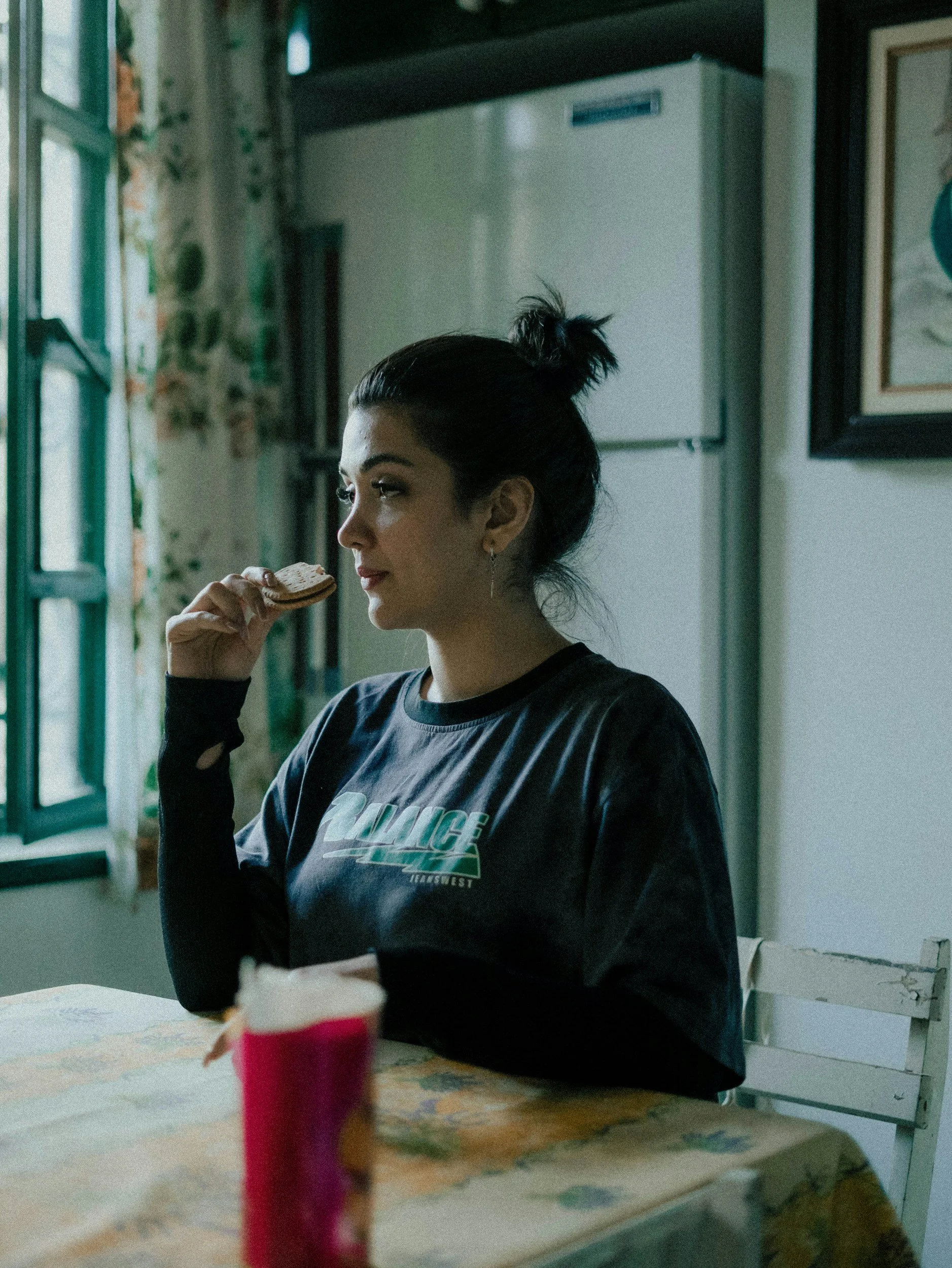 woman sitting at table with food looking thoughtful and slightly tense while dealing with anxiety around eating