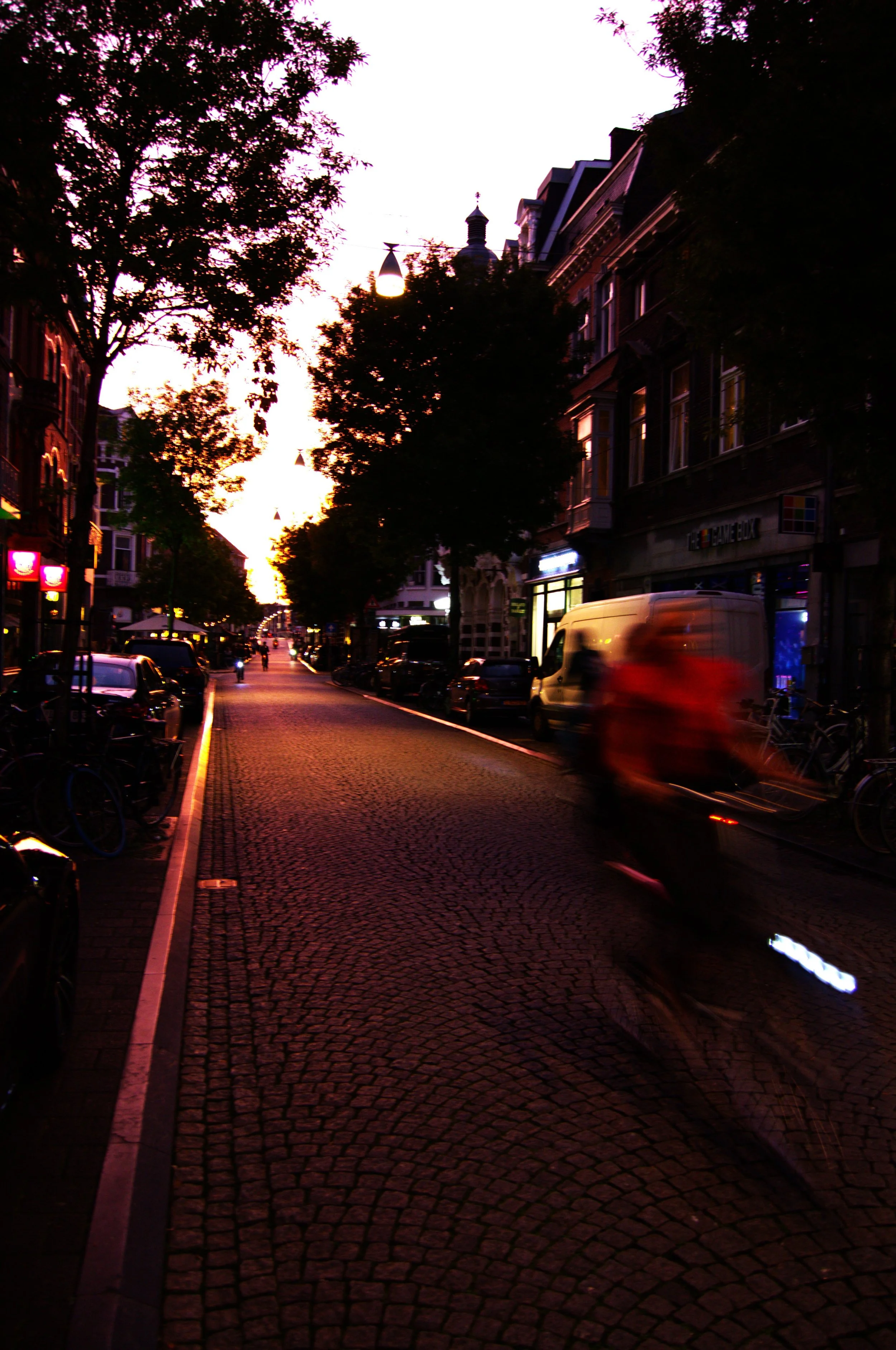 A street in Maastricht, the Netherlands. A bycicle passing by while the sun sets down into dusk.