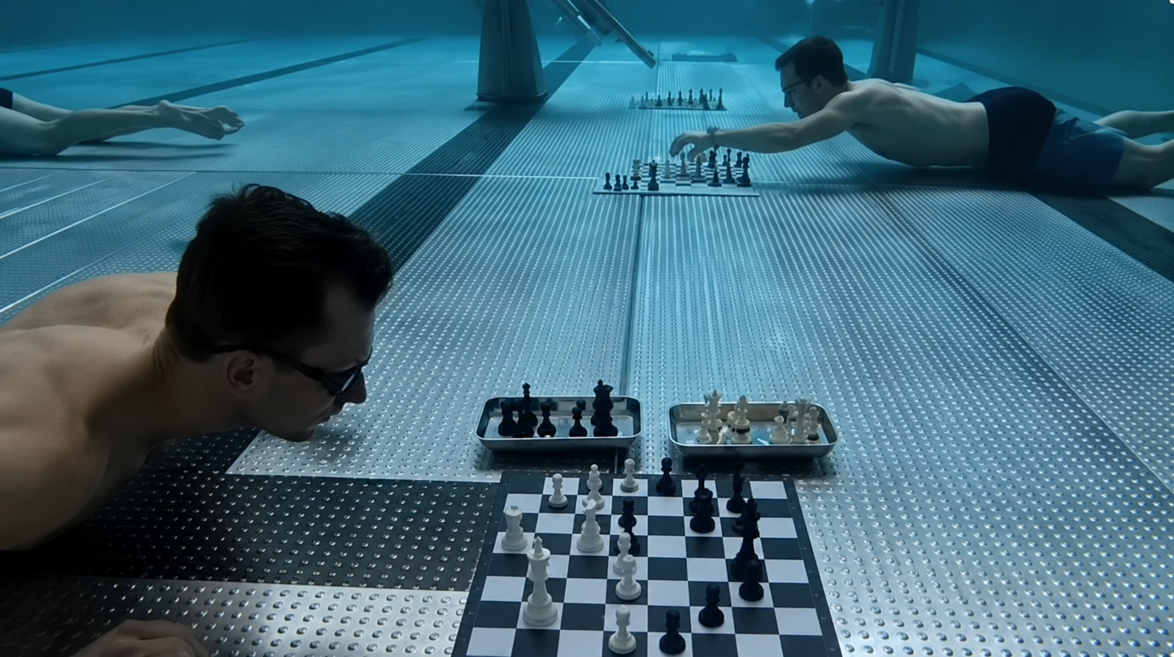 Divingchess game in a swimming pool with two divers playing on the pool floor, running out oxigen.