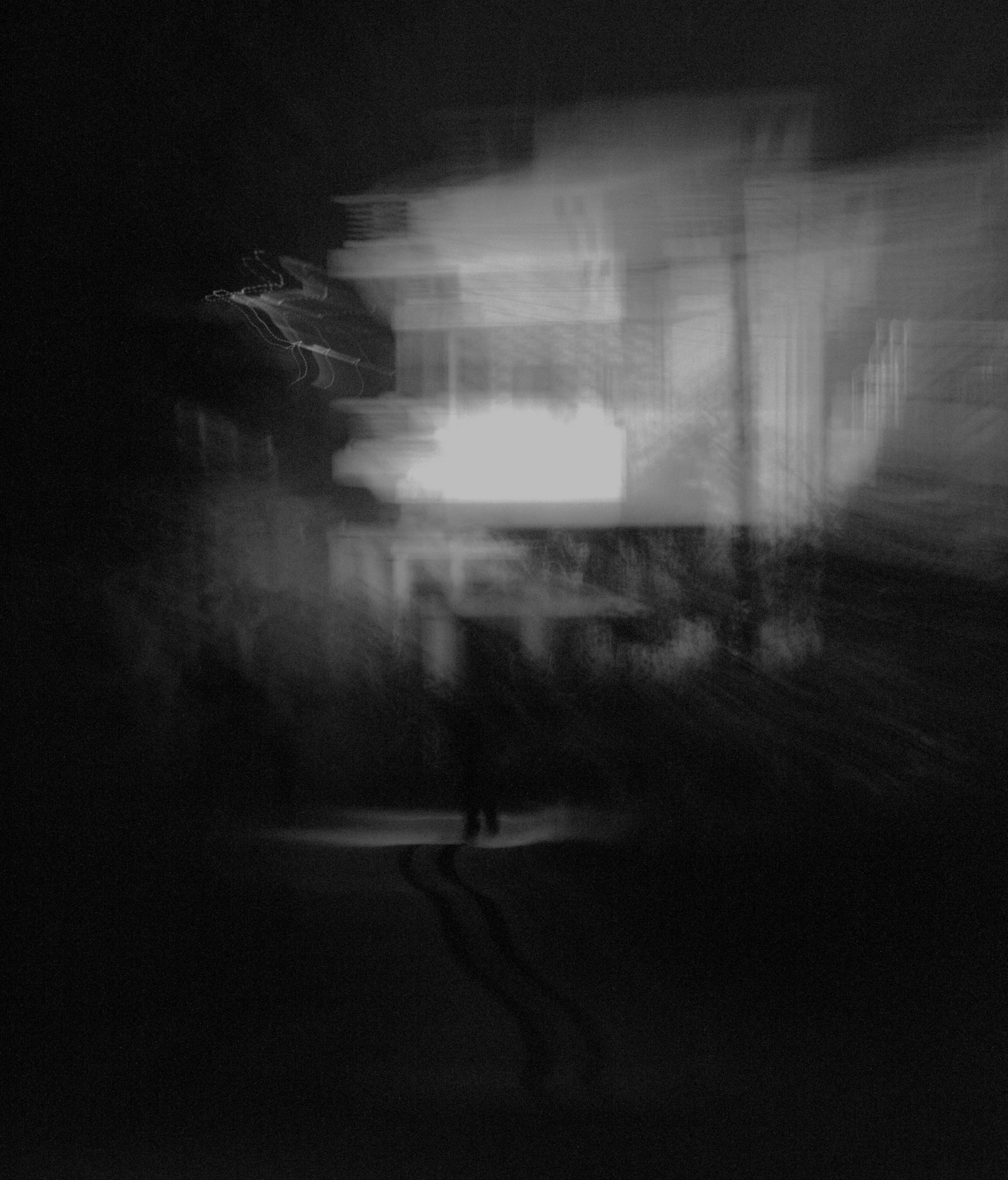 A photo taken in Kuchalnagar, Coorg. A person walking in a dark alley, in front an unknown building.