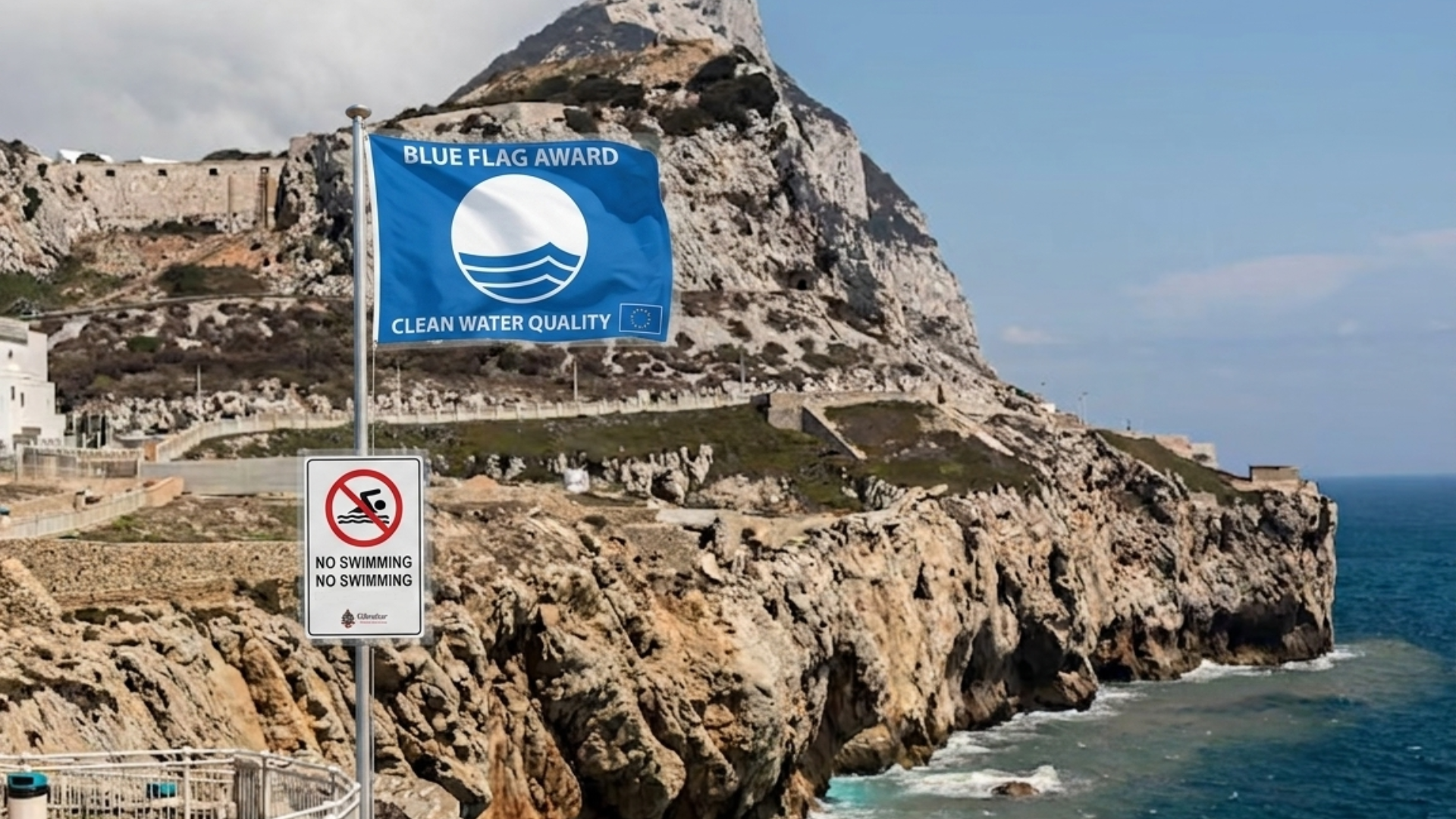 Satirical view of the Rock of Gibraltar with a European Blue Flag Award for clean water and a No Swimming sign mounted on the foreground railing, representing local environmental contradictions.