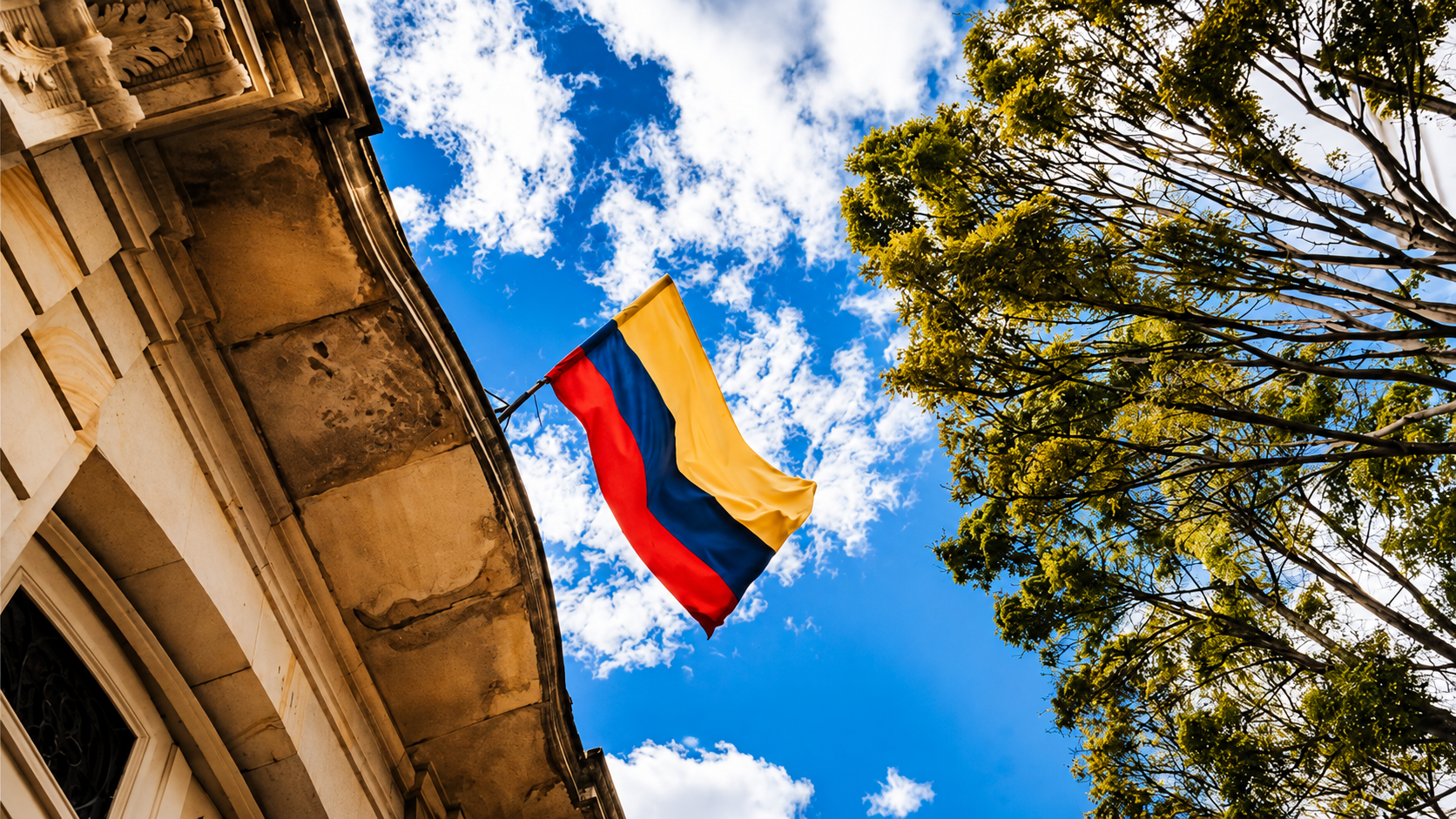 Bandera de Colombia ondeando frente a un edificio histórico bajo un cielo azul, símbolo de identidad, memoria y despertar de conciencia en Abriendo los ojos