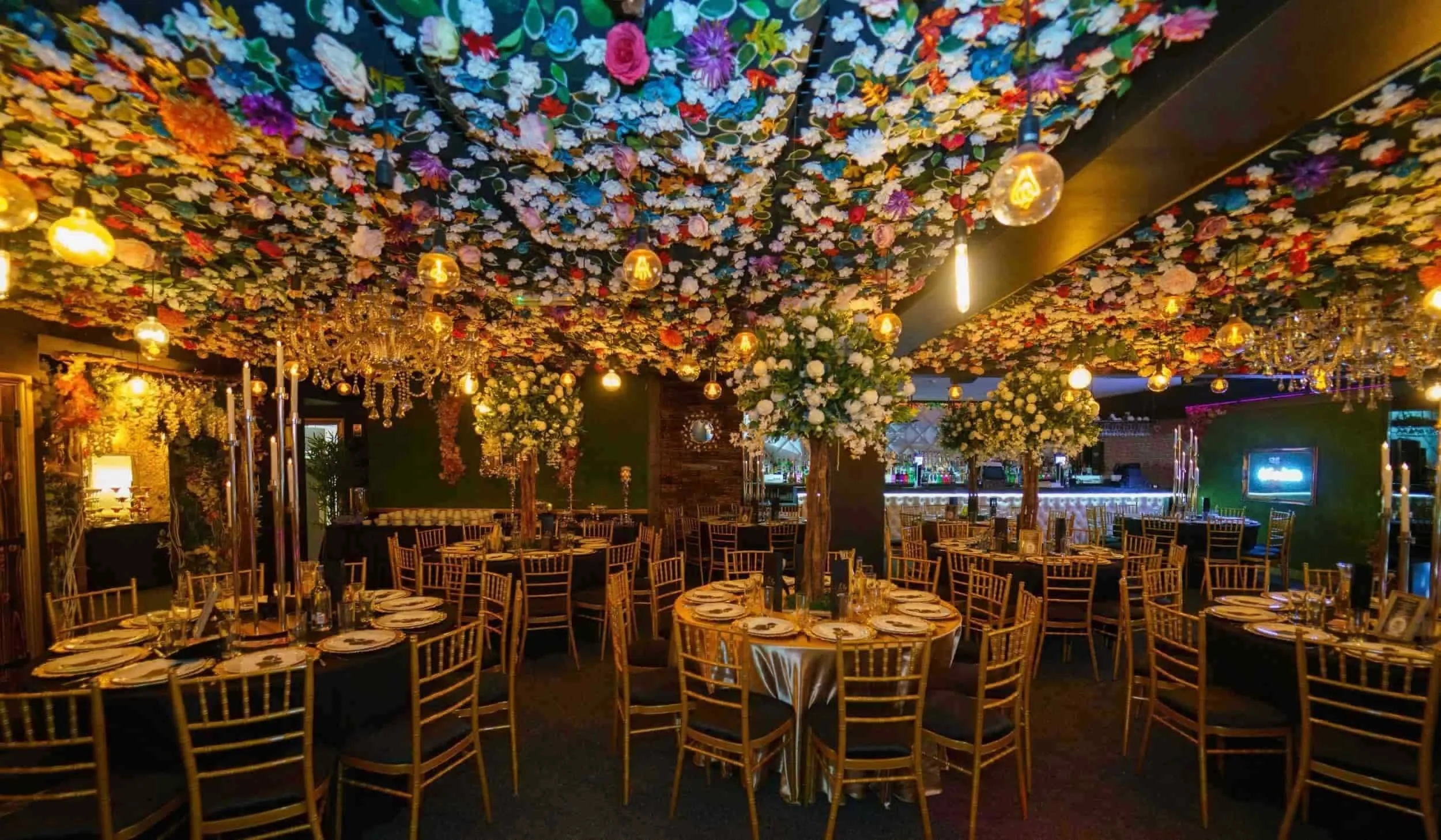 Luxury wedding reception venue with floral ceiling installation, chandeliers and elegant dining tables